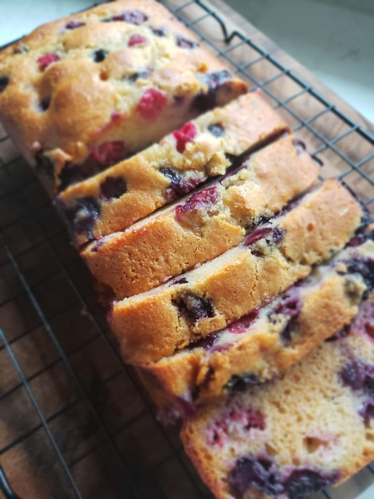 Sliced blueberry loaf cake cooling on a wire rack.