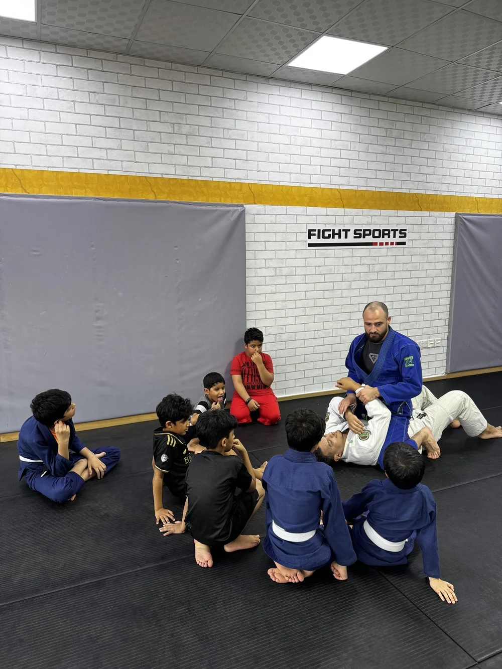 Children learning Brazilian Jiu-Jitsu with their coach at Fight Sports Muscat