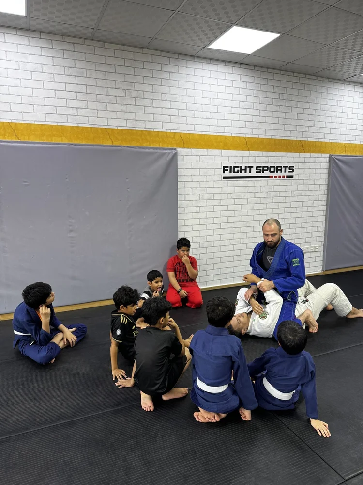 Children learning Brazilian Jiu-Jitsu with their coach at Fight Sports Muscat