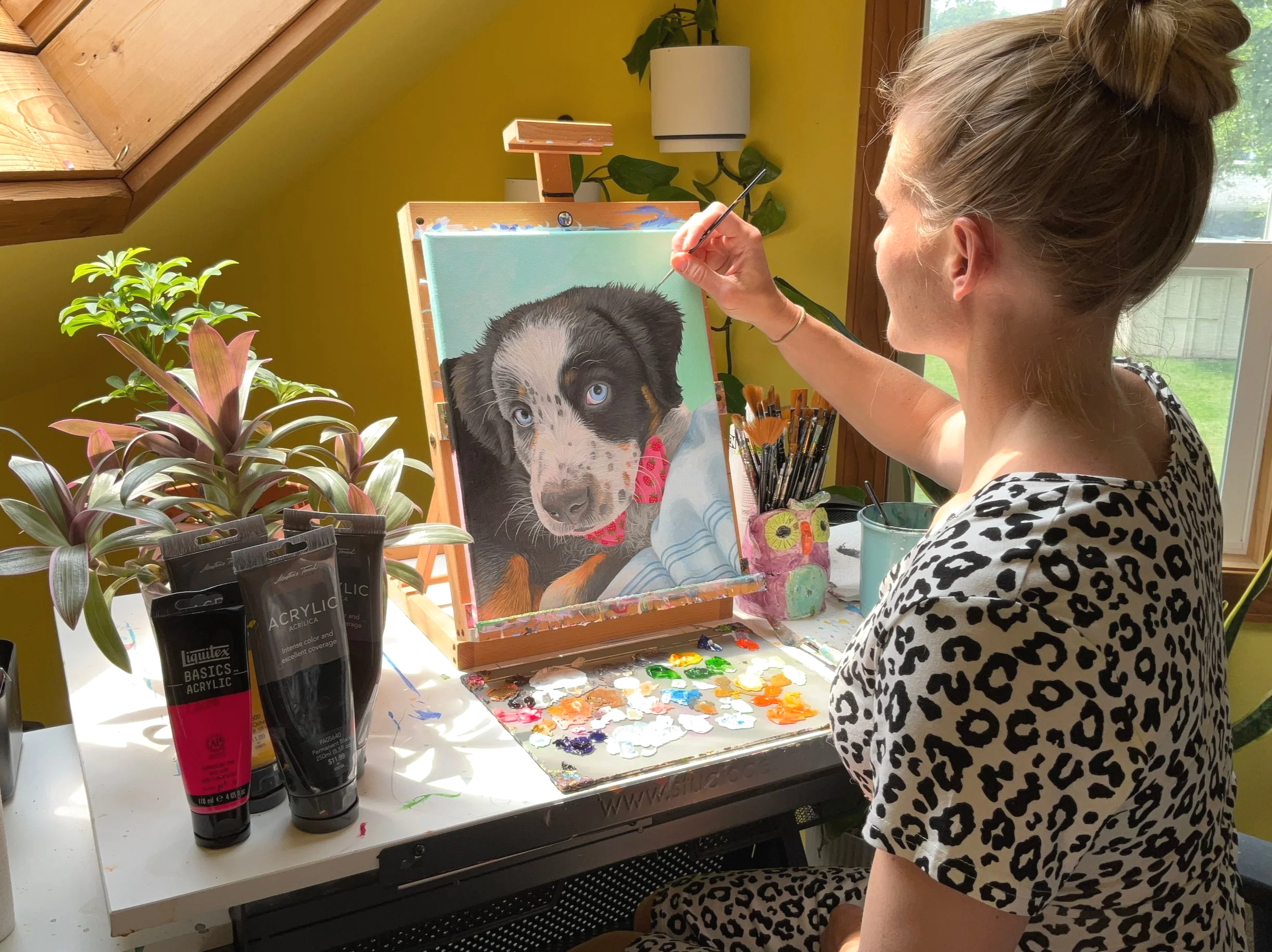A woman painting a realistic, colorful dog portrait in acrylics. A custom dog portrait commission.