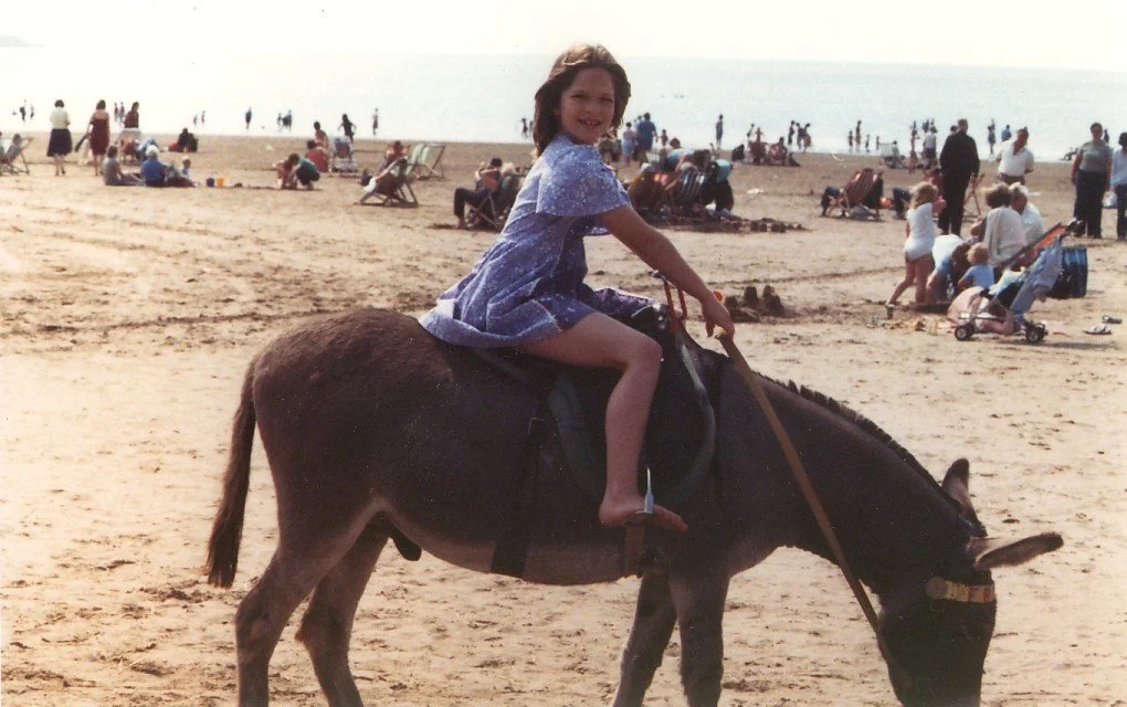 Mari Williams riding a donkey on the beach, childhood photo