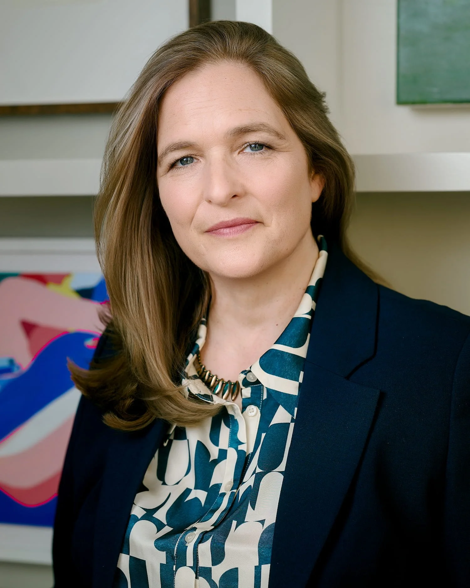 Mari Williams blue suit and blouse in front of art, working with teams and boards, executive therapy and performance under stress