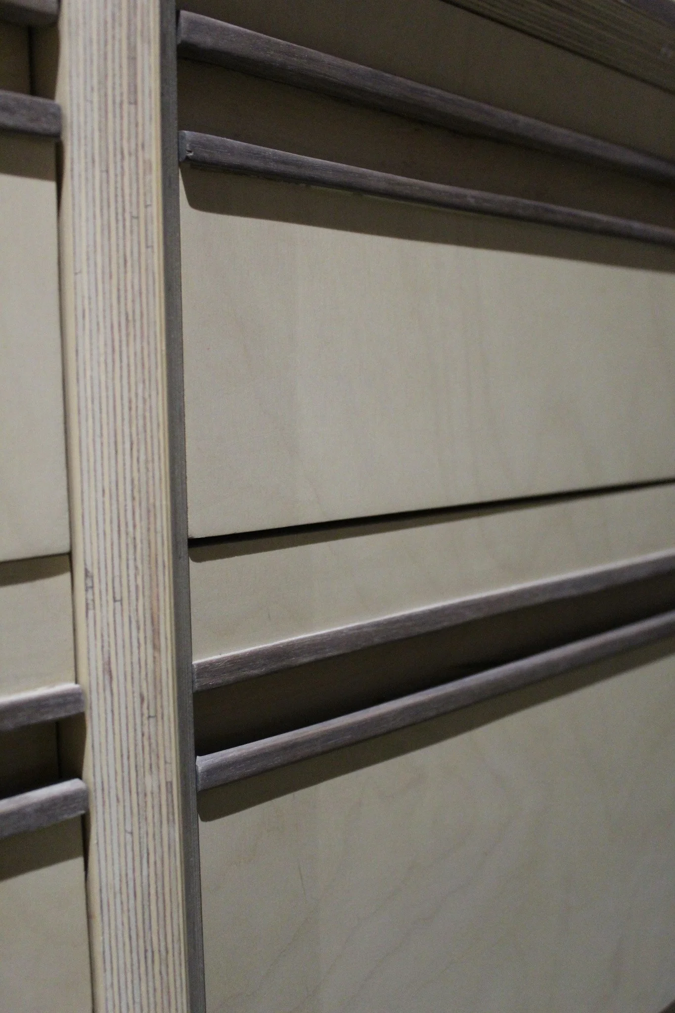 Close-up of a beige cabinet door with a wooden frame and horizontal metallic handles.