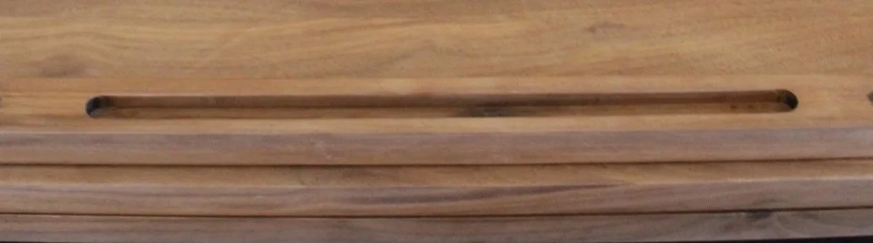 Close-up of a wooden drawer with a long slit handle.