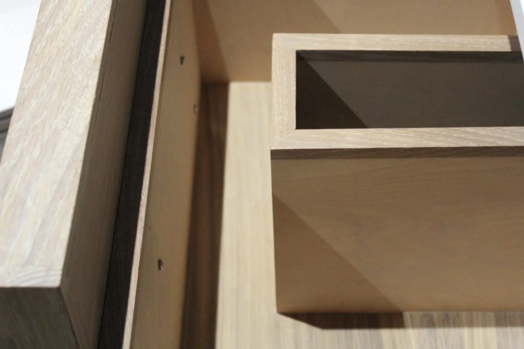 Close-up of an unfinished wooden cabinet or shelf with rectangular compartments, showing the natural wood grain and joints.