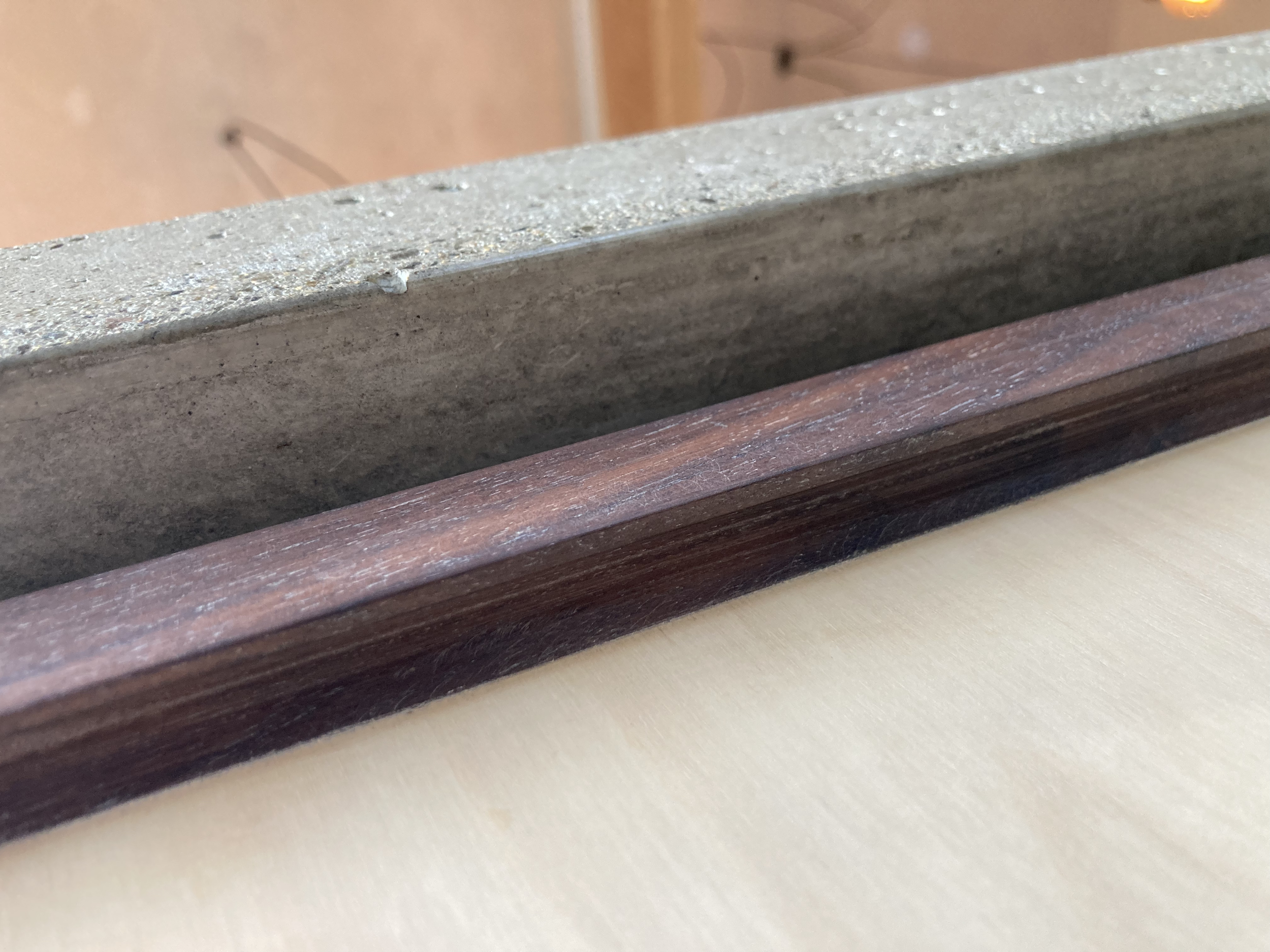 Close-up of a wooden and concrete edges of a surface, possibly a table or countertop.