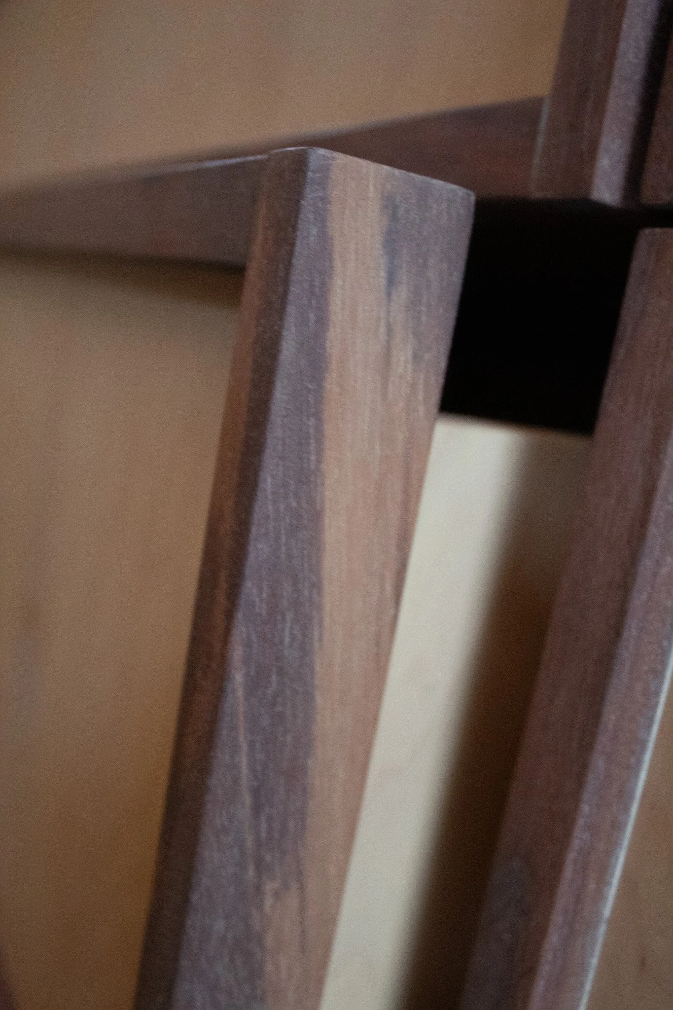 Close-up of a wooden furniture leg, showing the grain and slightly rounded edges.