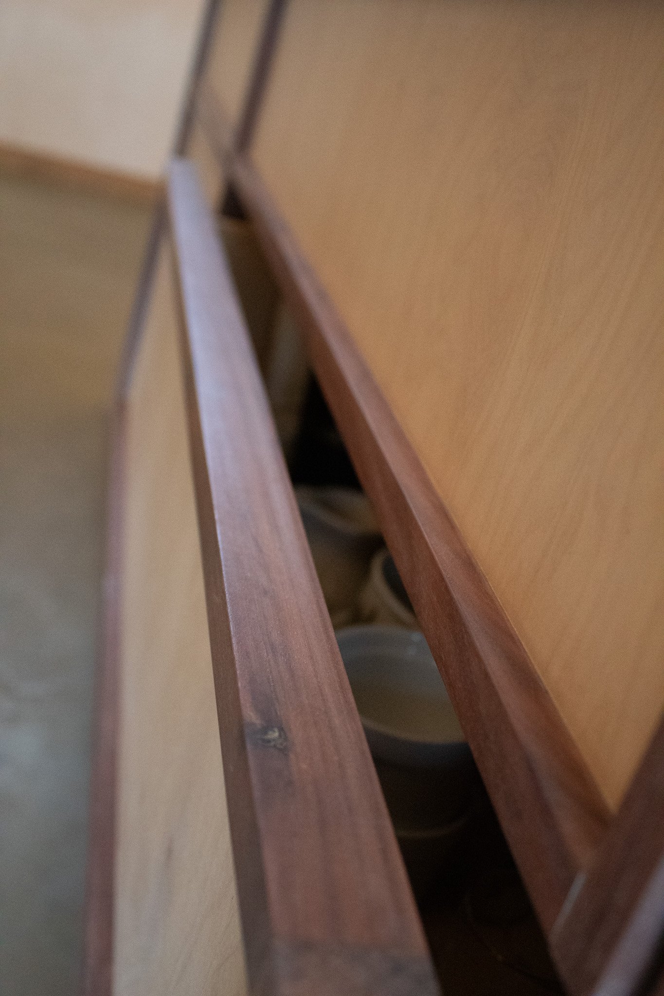 Close-up of a wooden cabinet drawer, partially open, revealing ceramic bowls inside.