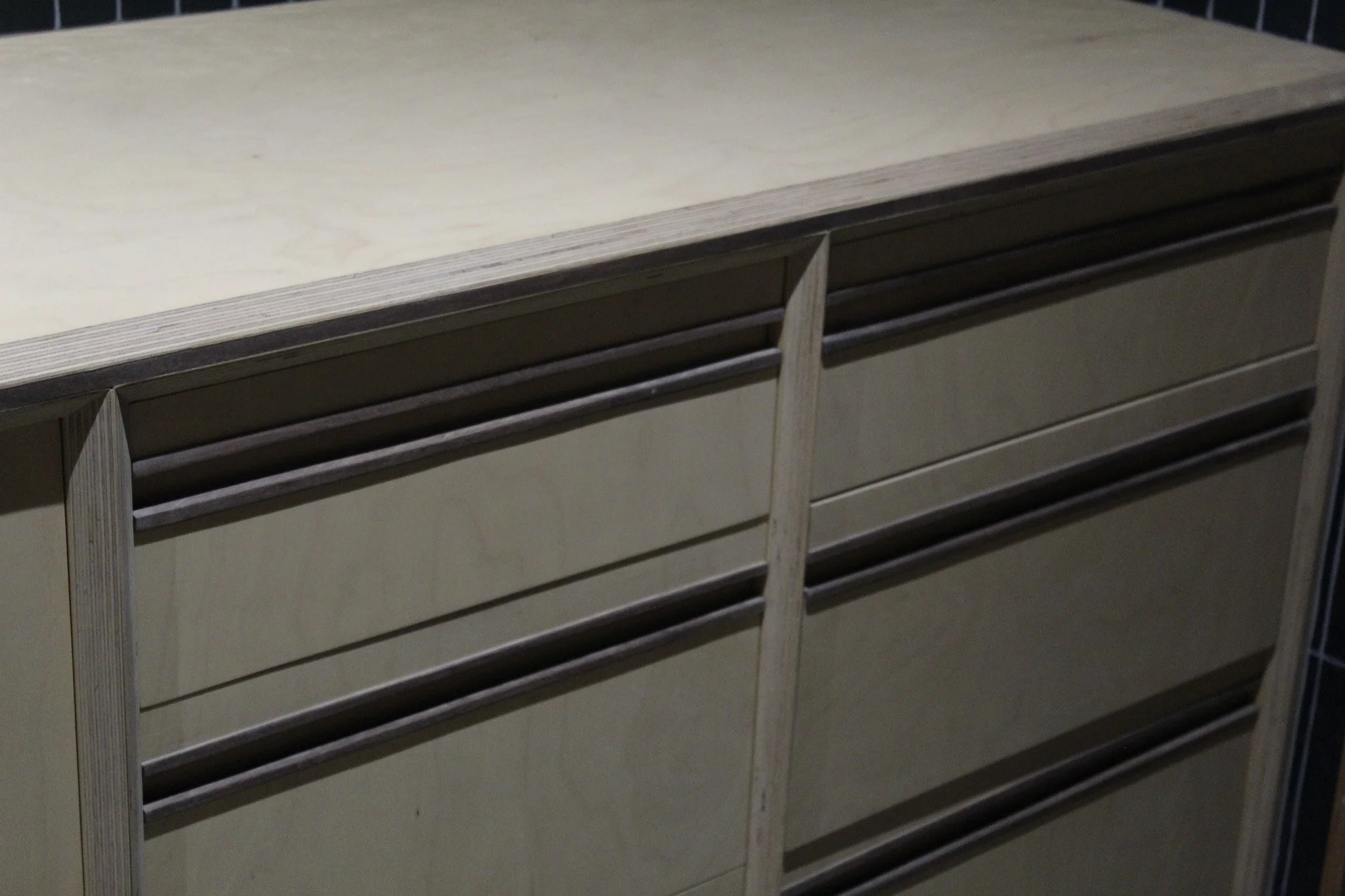 Close-up of a wooden dresser with multiple drawers, some of which are open, revealing support rails.