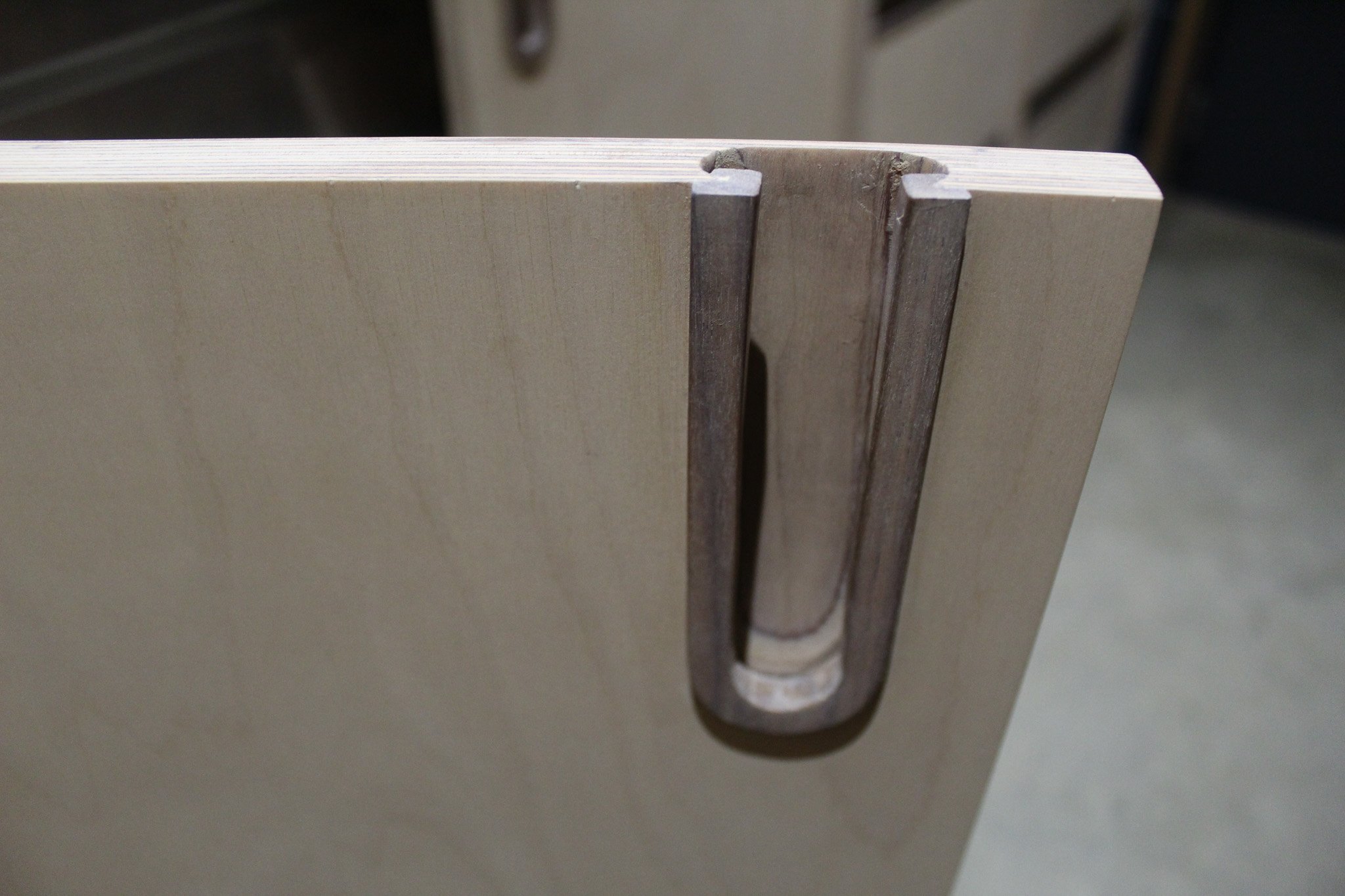 Close-up of a drawer slide mechanism attached to the edge of a wooden drawer.