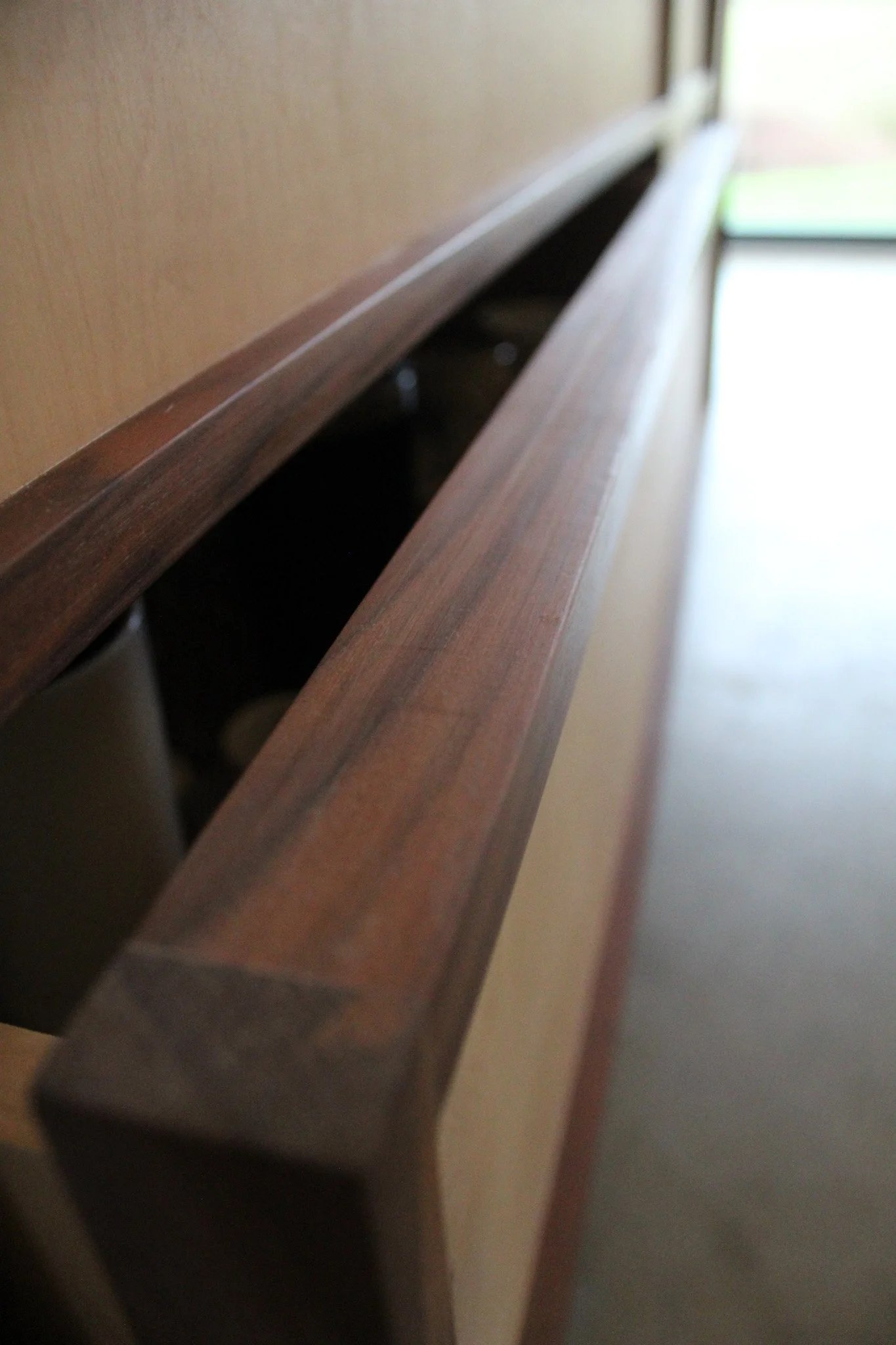 Close-up of a wooden headboard with a slit for a rail, part of a bed frame.