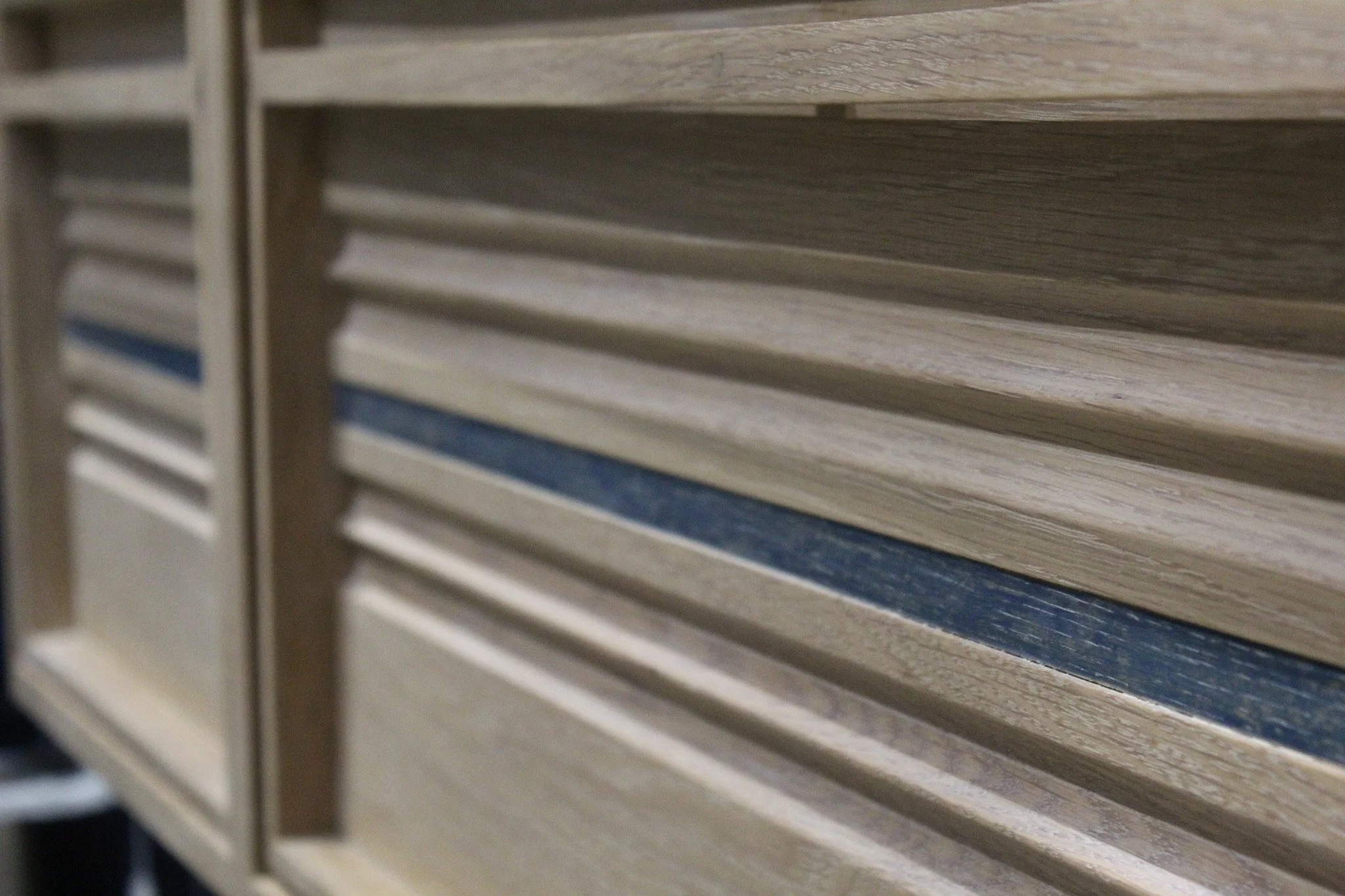 Close-up of a wooden slatted bench or shelf with a blue stripe detail.