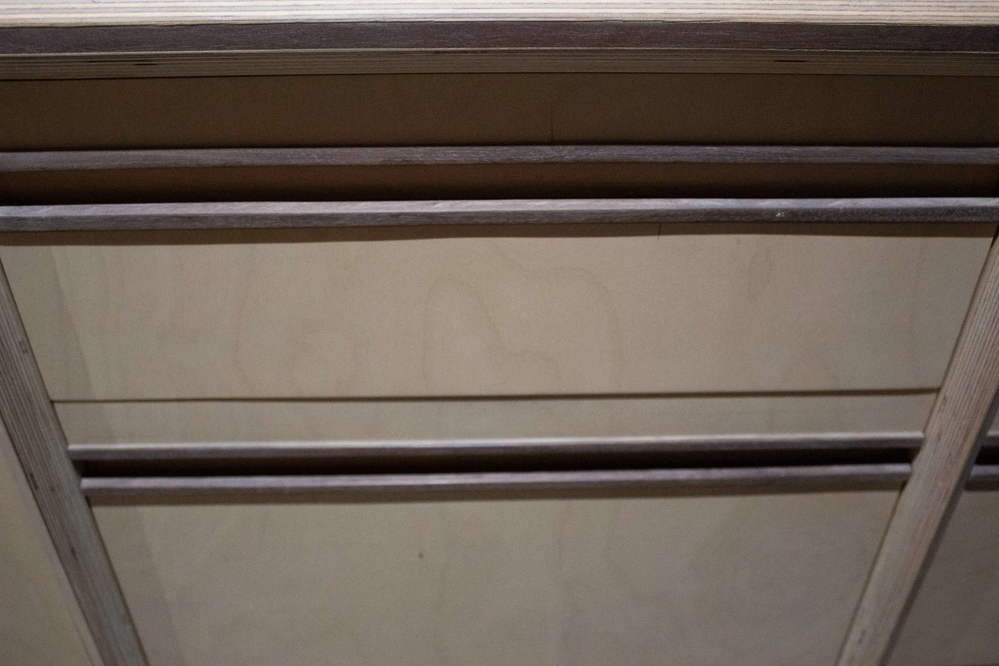 Close-up of a ceiling with wooden beams and beige panels.