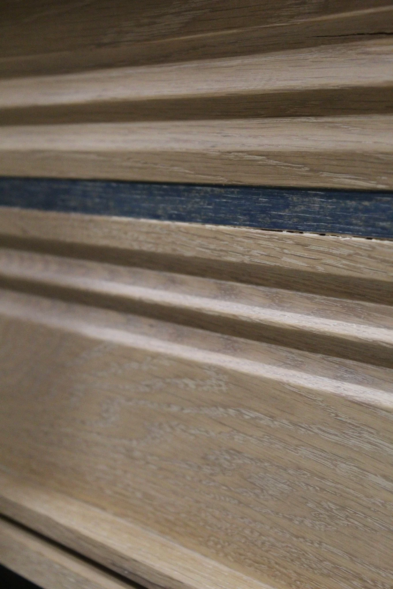 Close-up image of horizontal wooden slats or panels, with one darker strip in the middle.