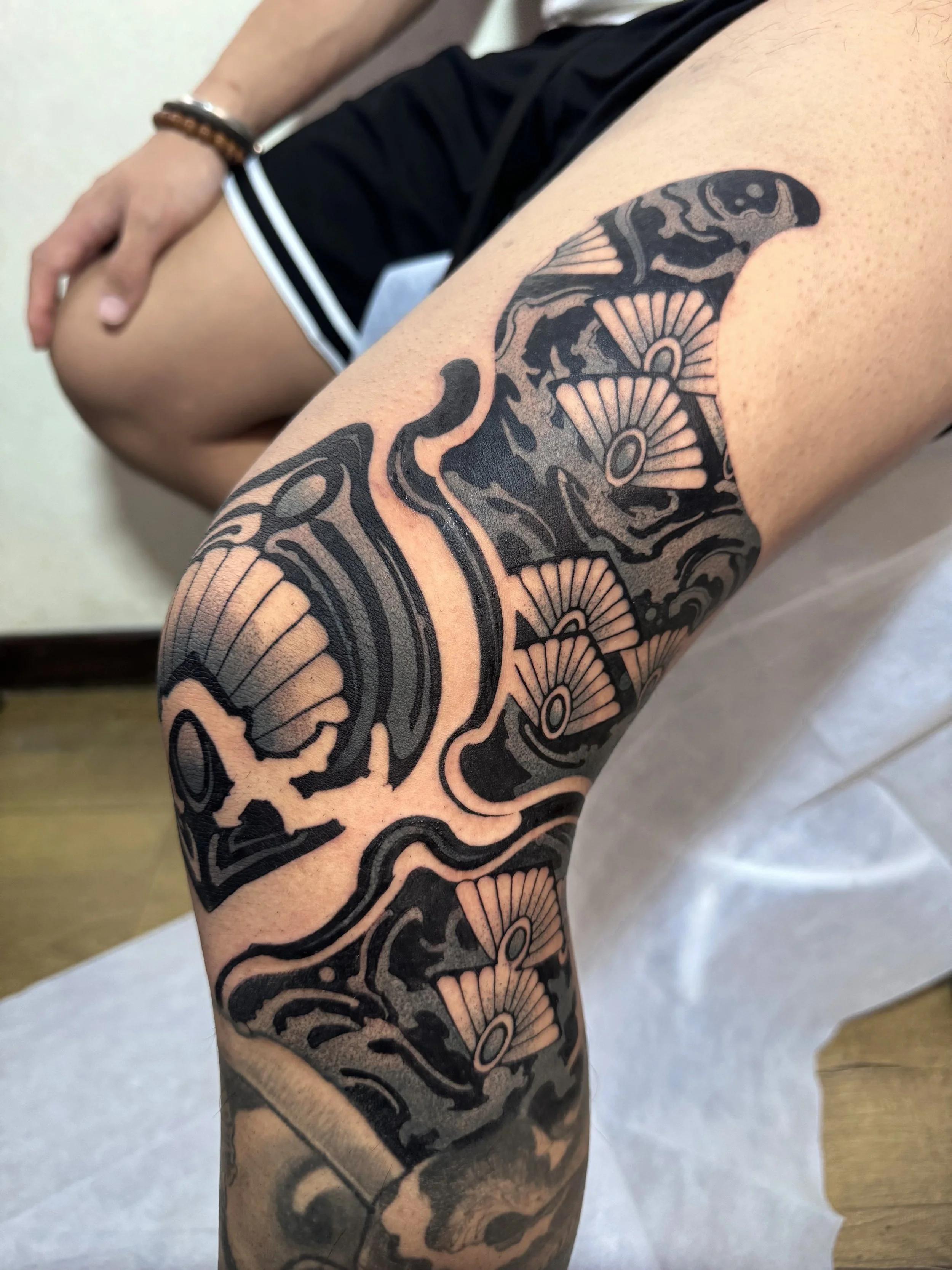 Close-up of a tattooed arm showing detailed black ink tattoo with floral and intricate patterns.