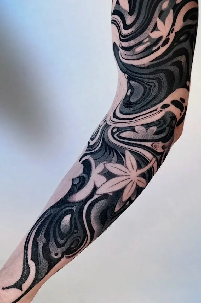 Tattoo sleeve with black and pink swirled patterns and floral designs on a person's arm.