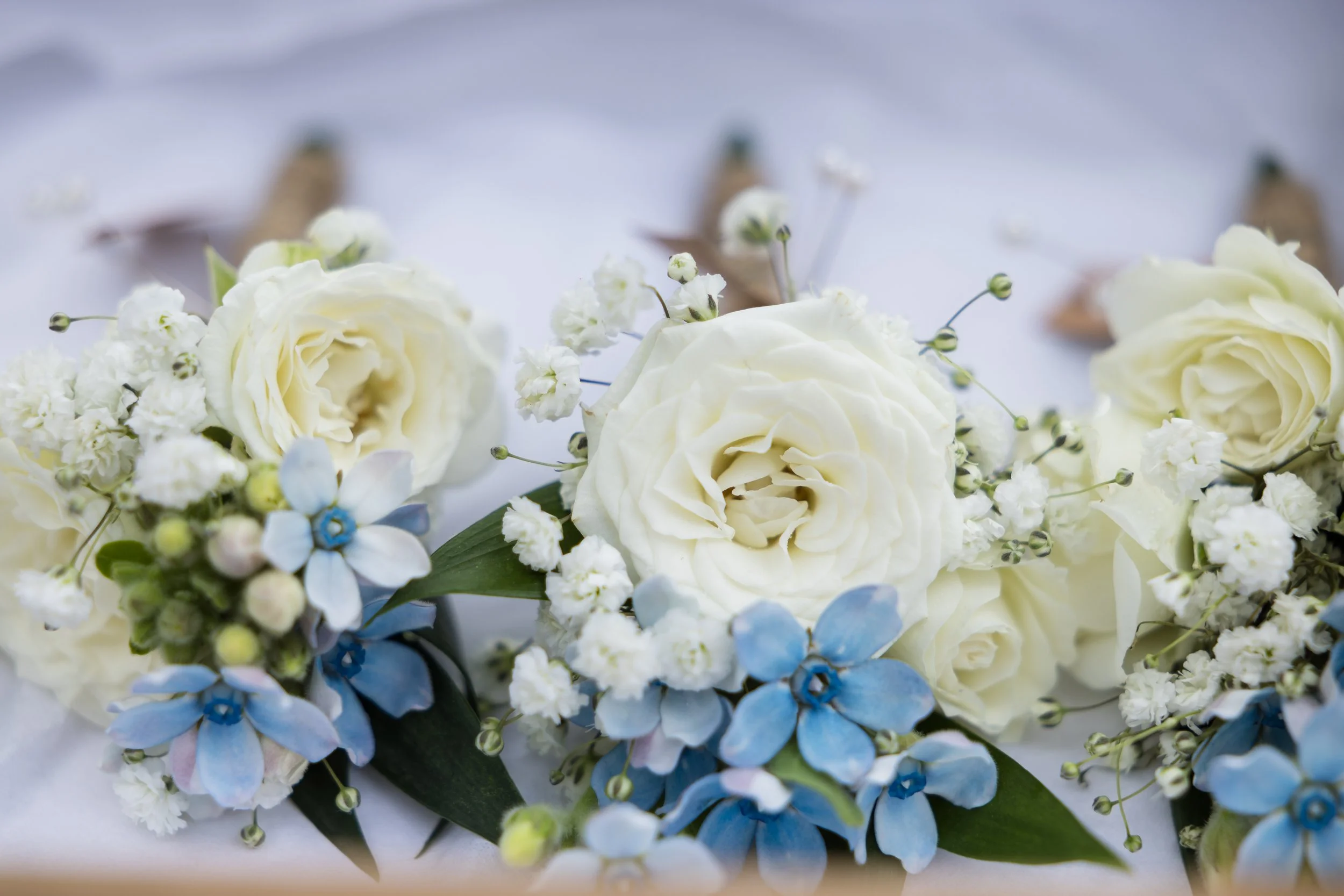 White and blue floral arrangement with roses, small white flowers, and greenery