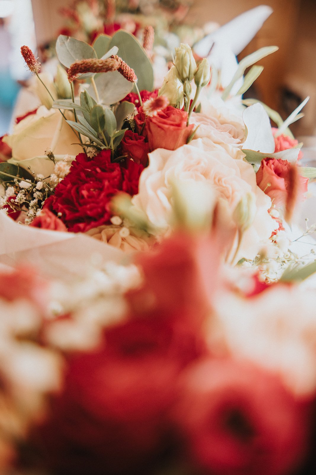 Close-up of a colorful flower bouquet with various pink, white, and red flowers and green leaves.