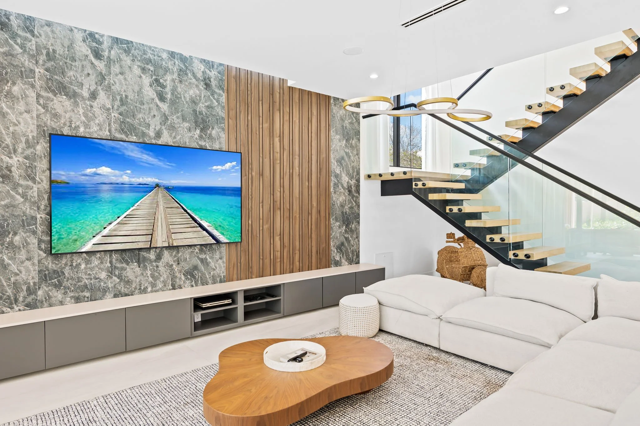 Elegant living room with gold chandelier, marble and wood accent walls — design-forward vacation home, Sun Haven Collection.