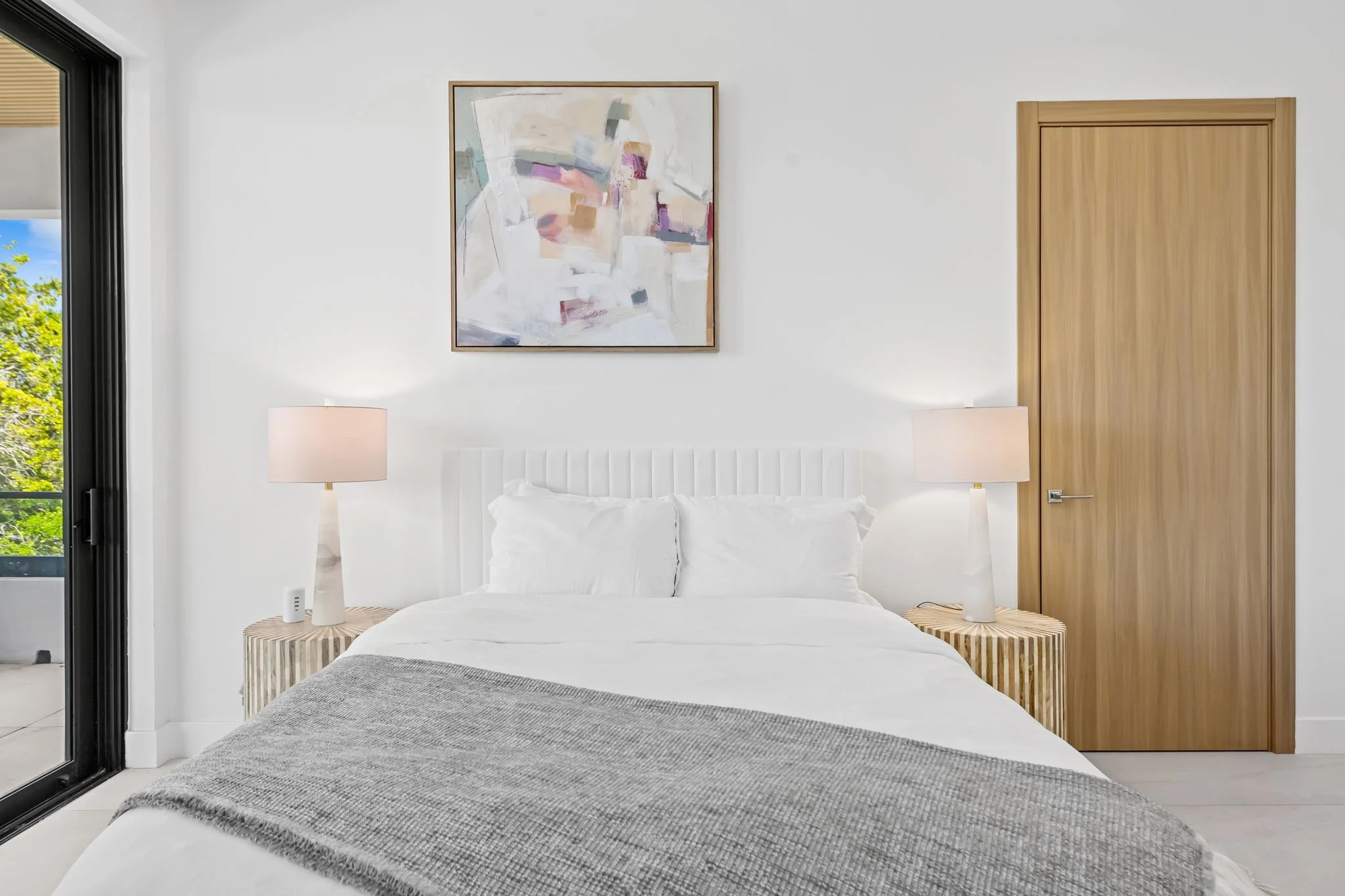 Serene bedroom with abstract artwork and natural light — luxury vacation rental, Sun Haven Collection.