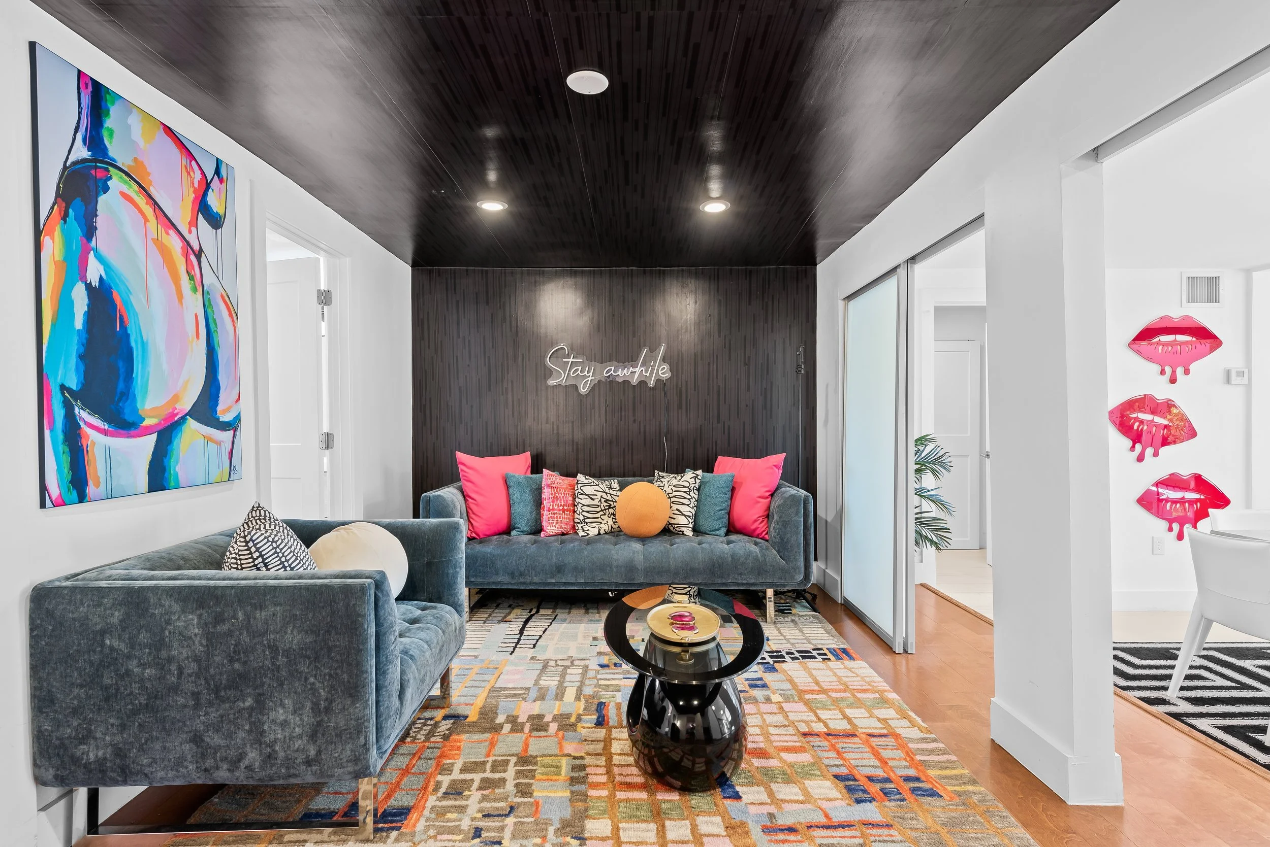 Designer living room with neon signage, pop art, and geometric rug — luxury vacation home by Sun Haven Collection.