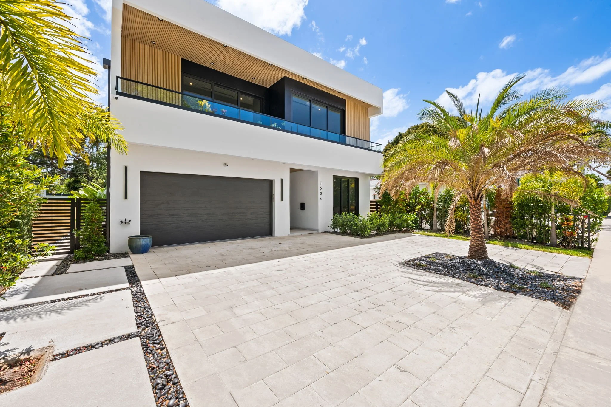 Modern luxury vacation home exterior with palm trees and landscaped entry — Sun Haven Collection rental.