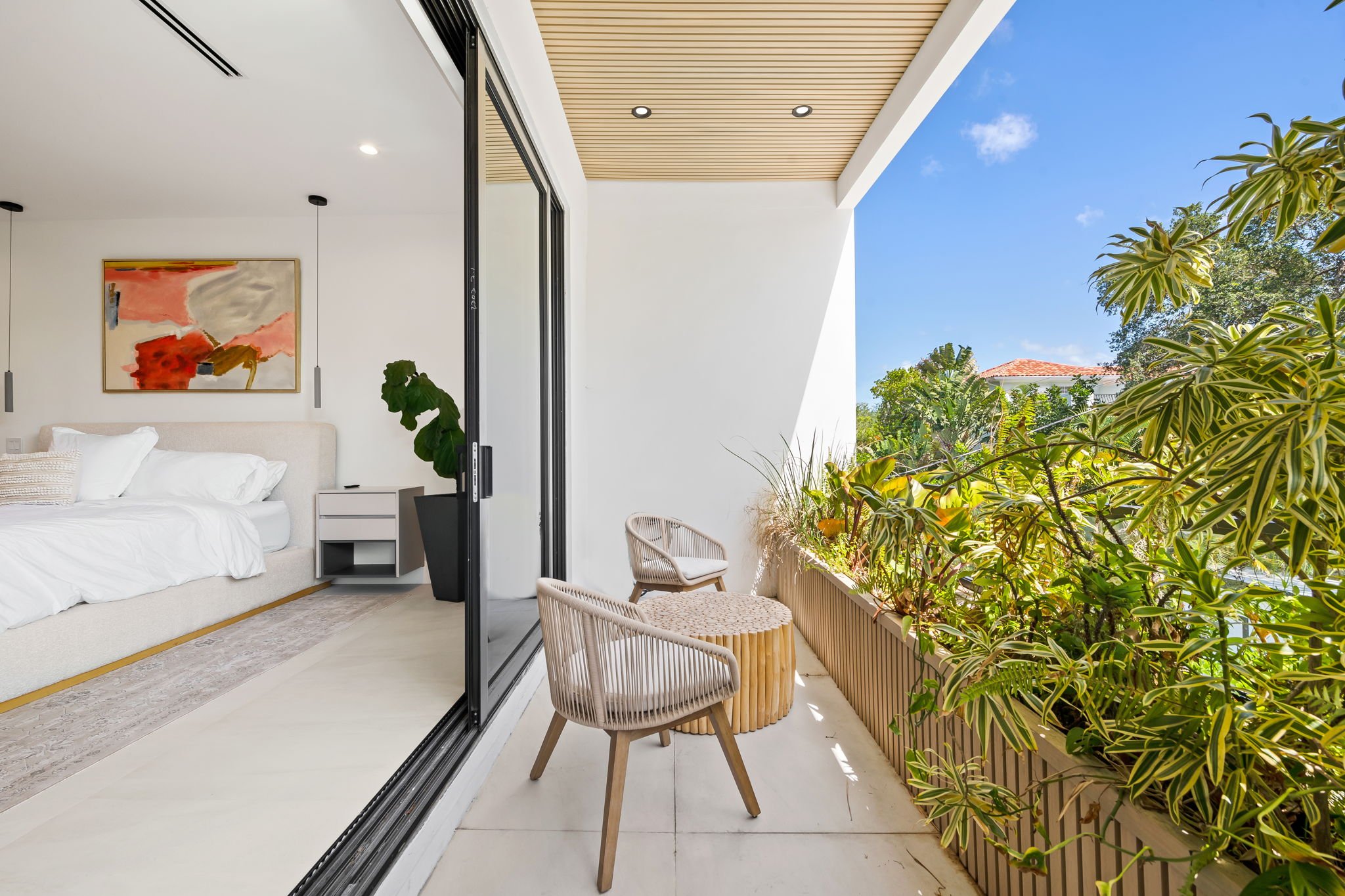 Private balcony with wicker seating overlooking lush tropical neighborhood — Sun Haven Collection vacation rental.