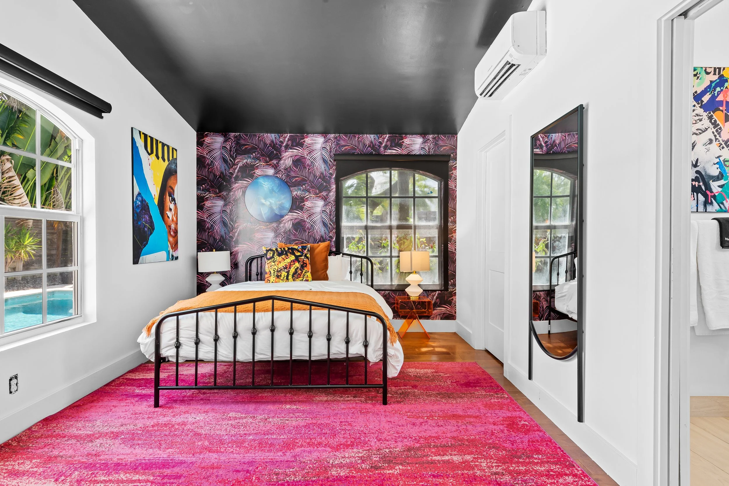 Bold bedroom with tropical accent wall and colorful pillows — Sun Haven Collection art-inspired vacation rental.