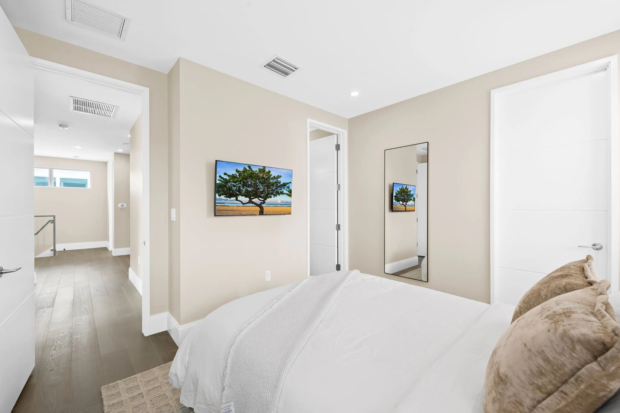 Bright bedroom with smart TV and full-length mirror — Sun Haven Collection luxury vacation rental.
