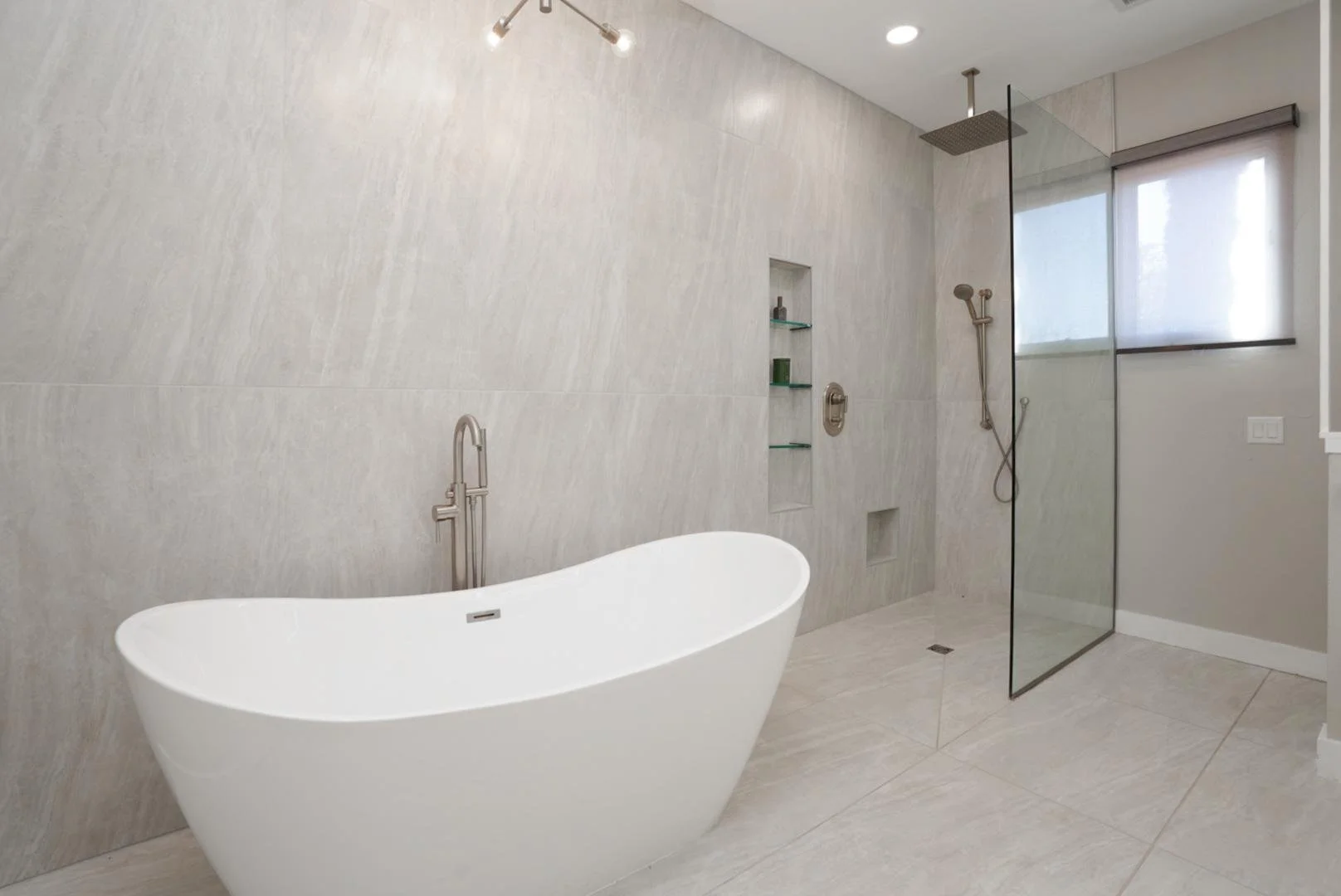 Modern bathroom with freestanding bathtub, walk-in shower with glass partition, and a window
