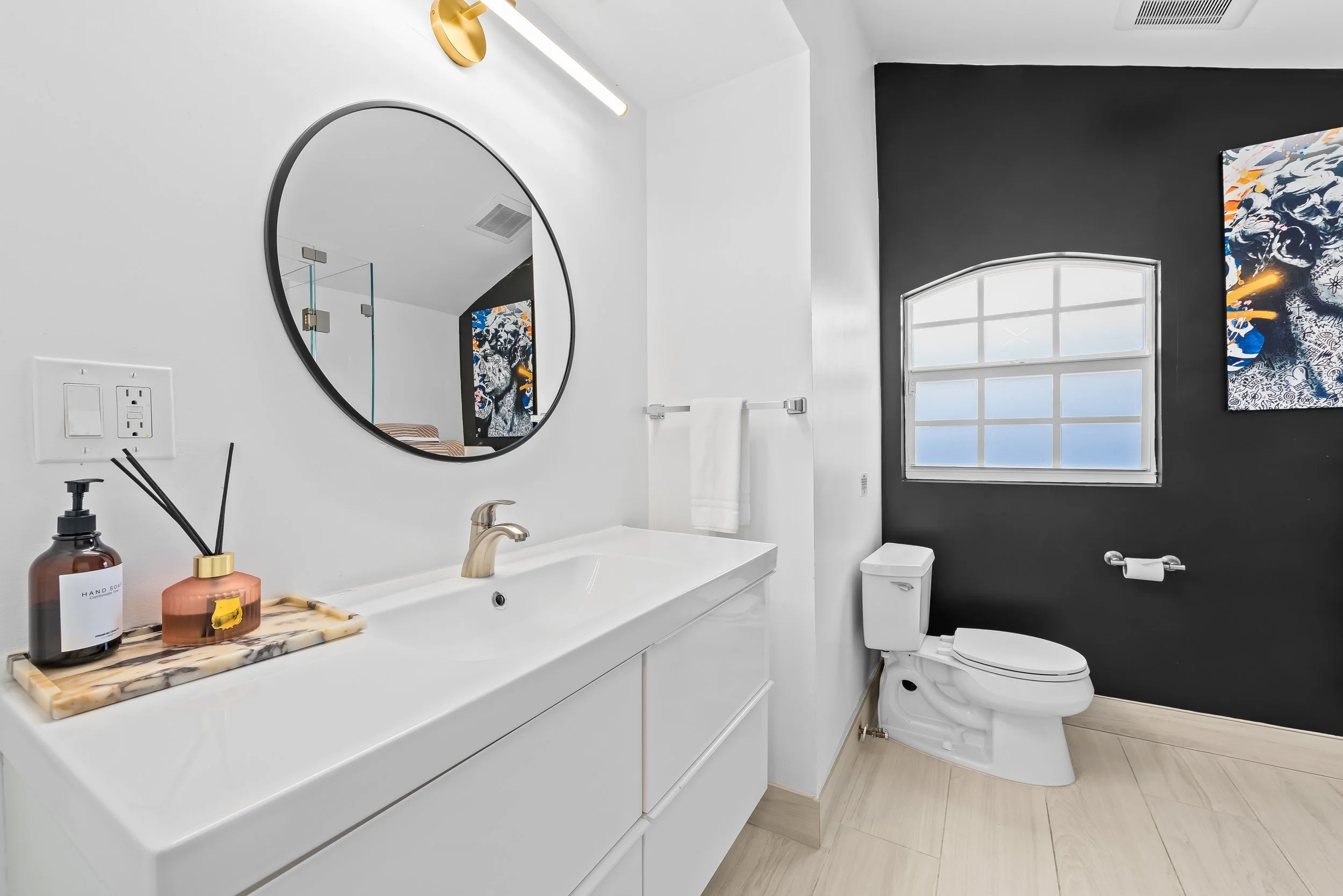 Designer bathroom with marble tray amenities and black accent wall — Sun Haven Collection luxury vacation rental.