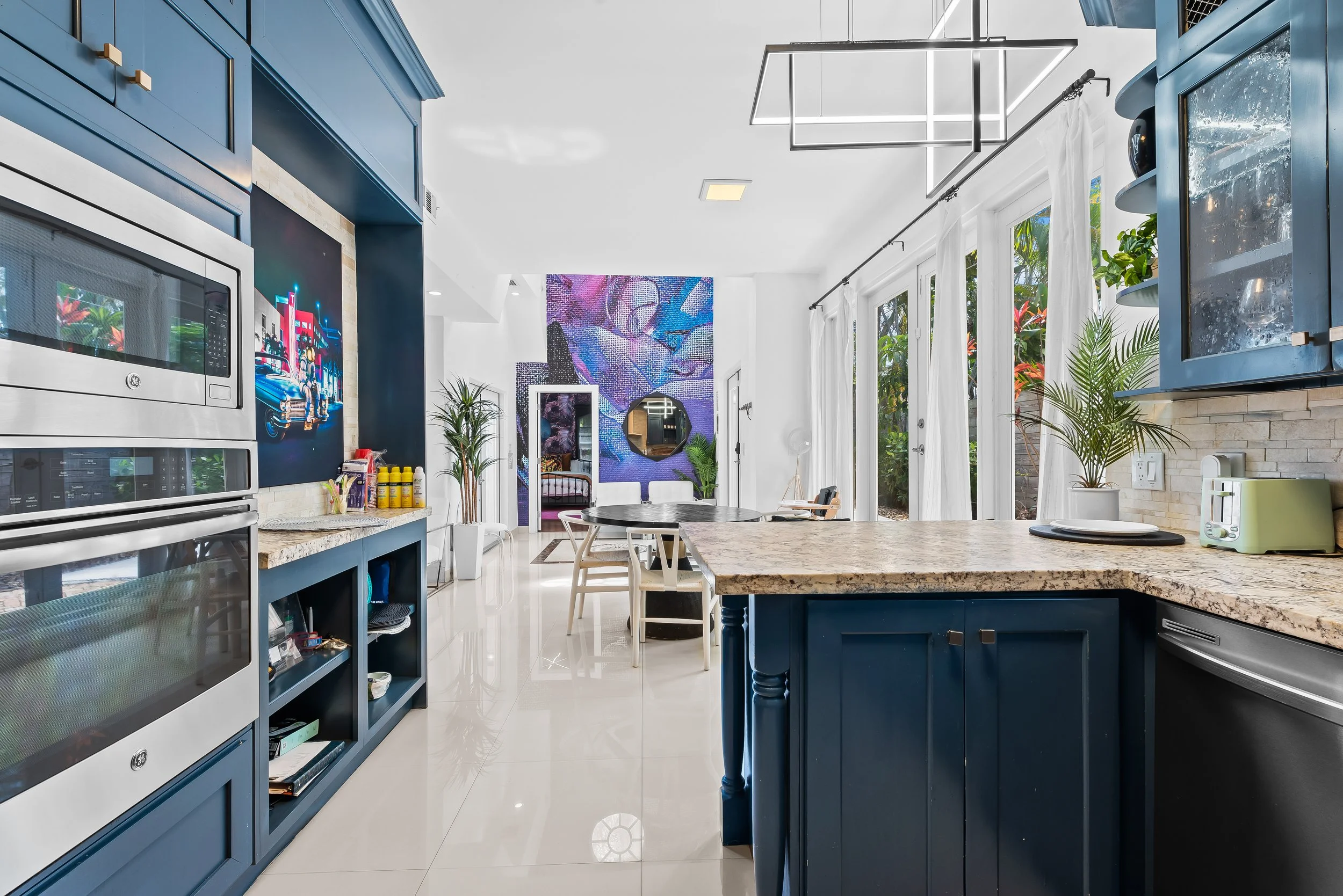 Modern kitchen and dining area with blue cabinets and natural light — luxury vacation rental, Sun Haven Collection.
