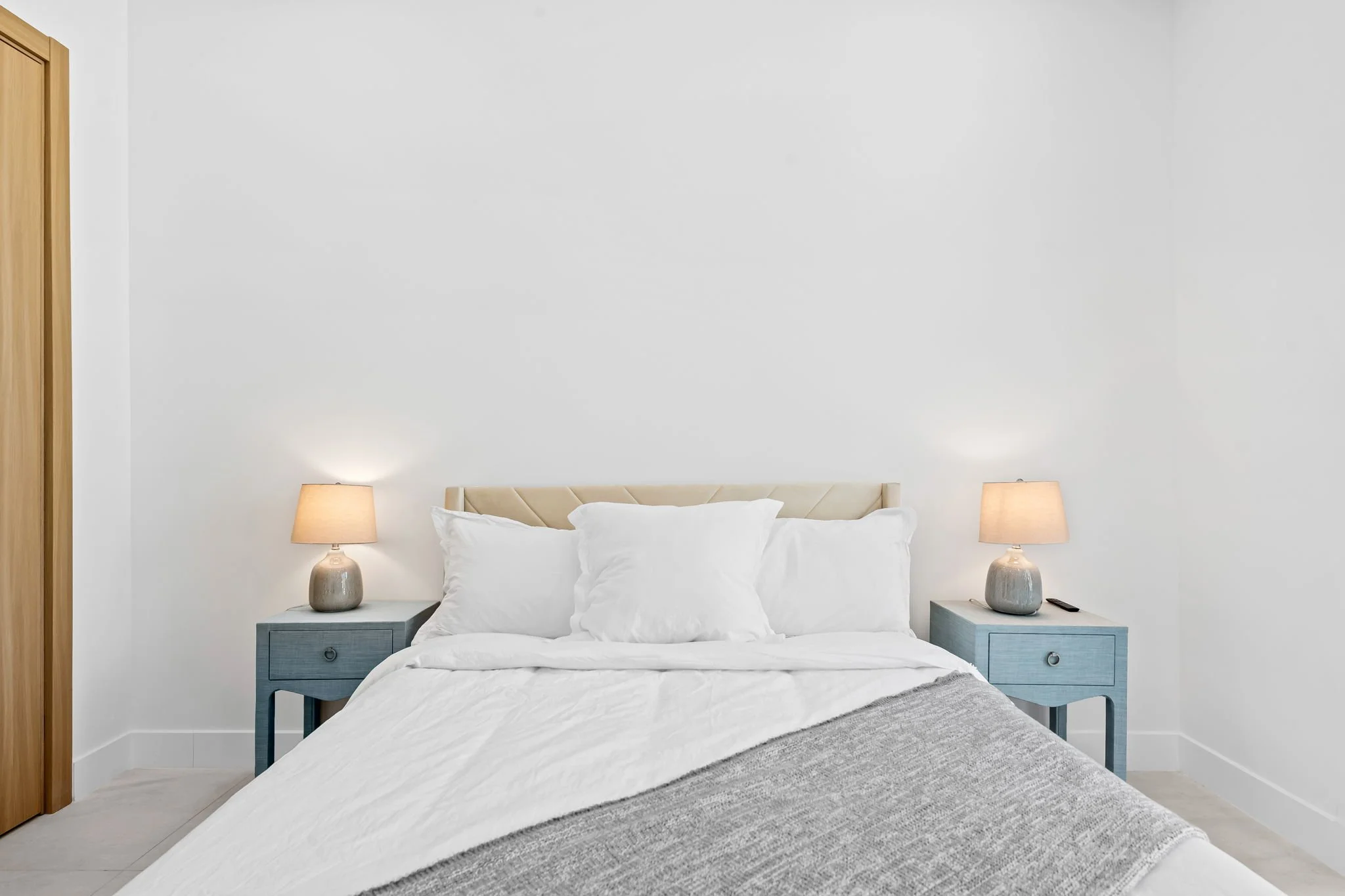 Minimalist guest bedroom with designer bedding and bedside lamps — luxury vacation home, Sun Haven Collection.