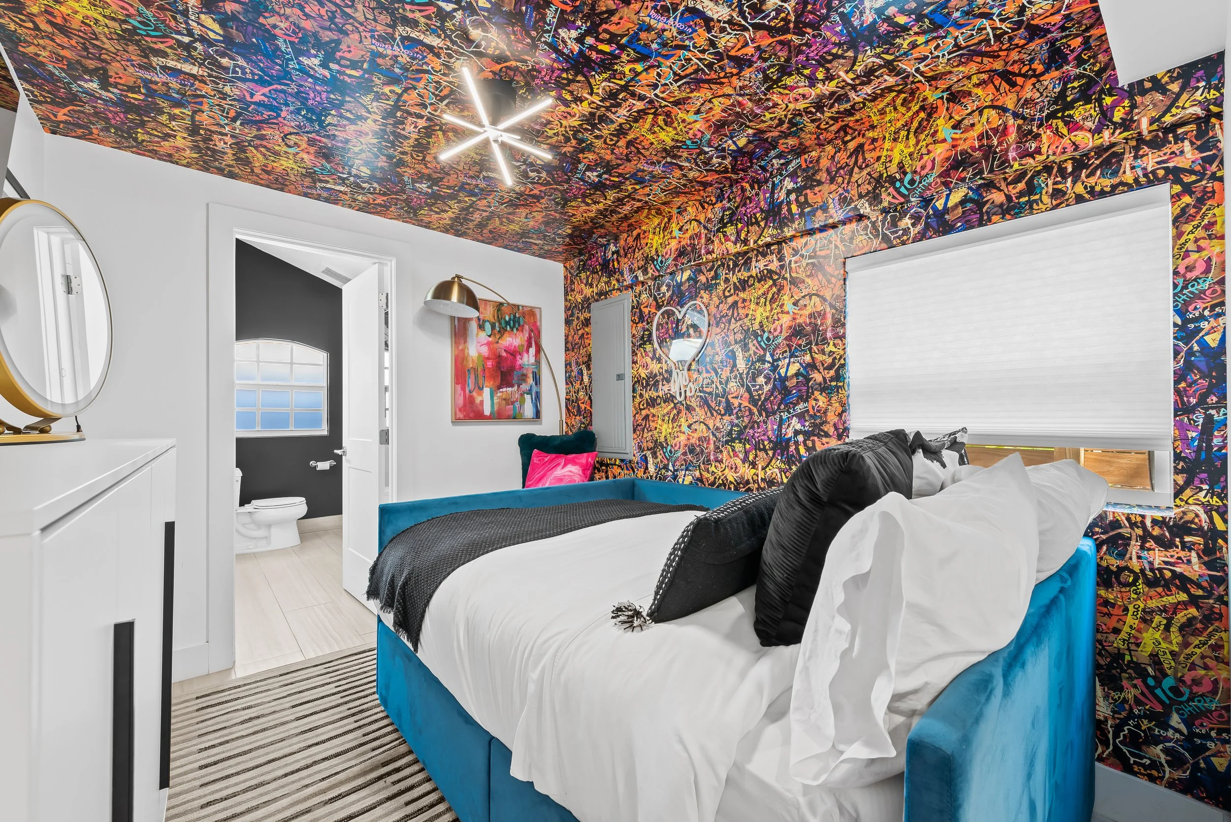 Statement bedroom with graffiti art ceiling and LED chandelier — Sun Haven Collection art-inspired vacation home.