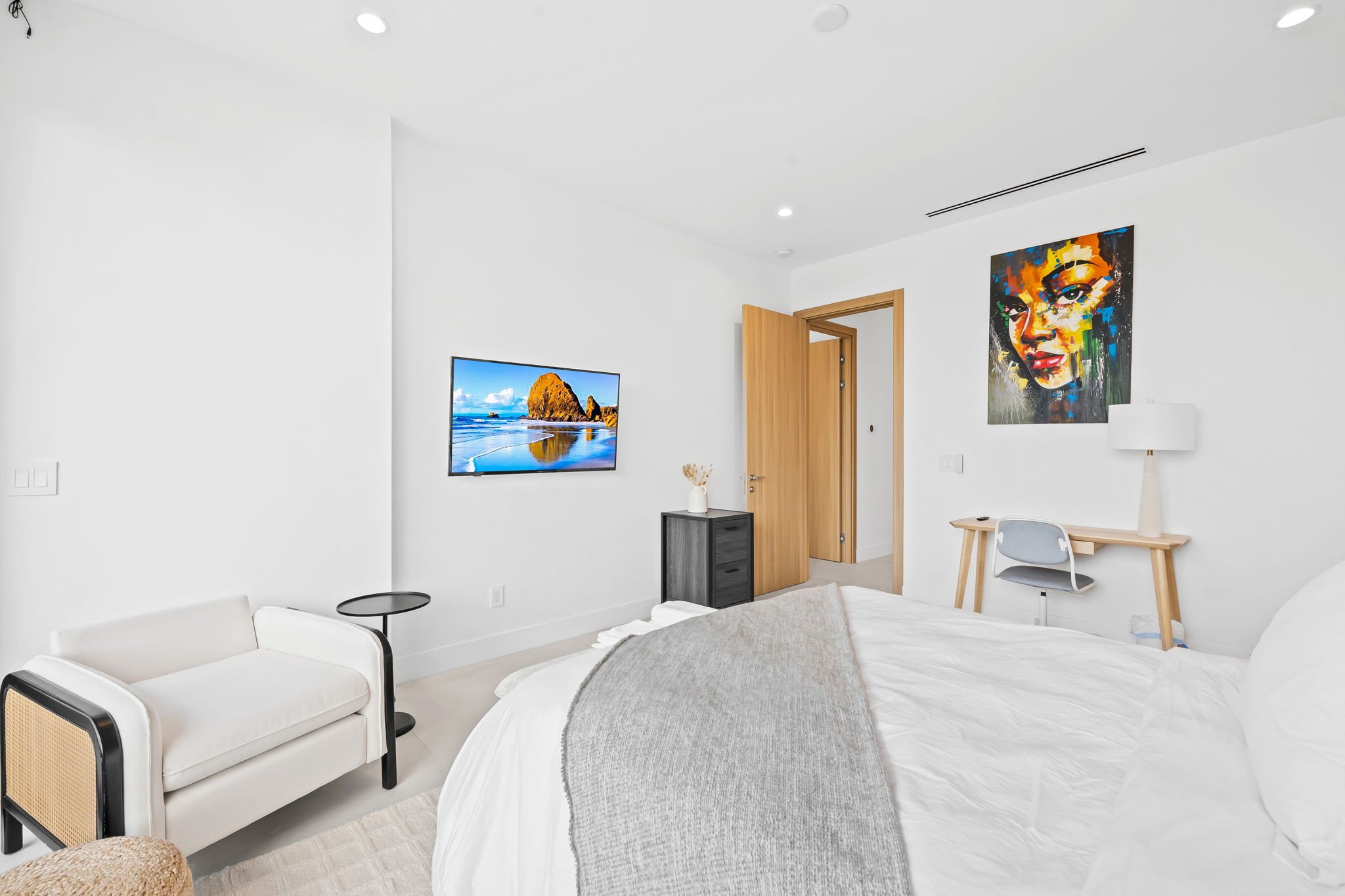 Modern guest room with curated portrait art and smart TV — Sun Haven Collection luxury vacation home.