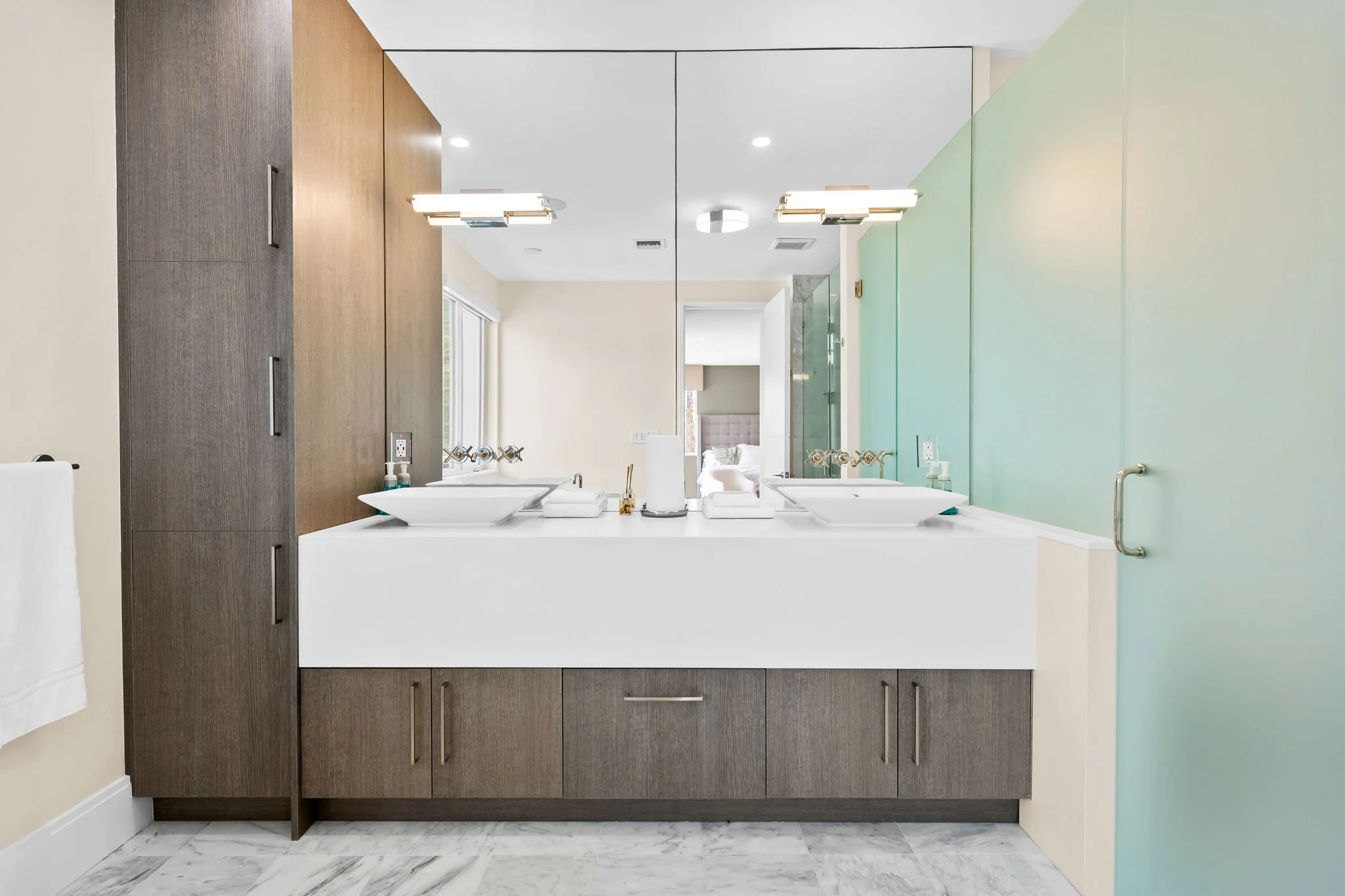 Dual-vanity bathroom with teal accent wall and dark cabinetry — Sun Haven Collection luxury vacation rental.