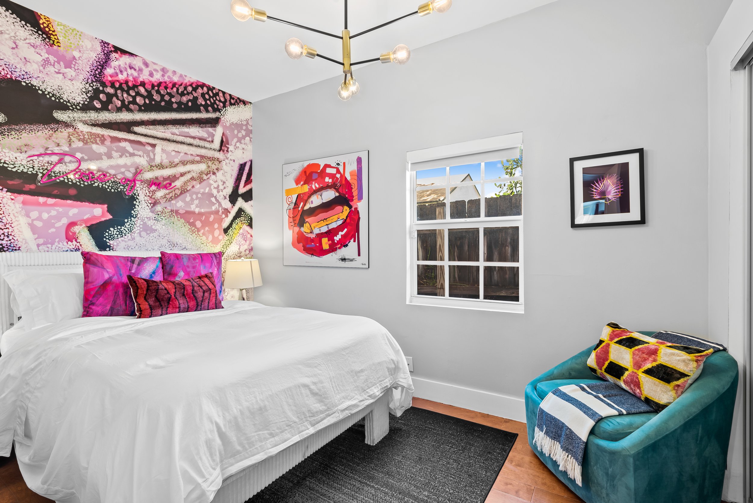 Pop art-inspired primary bedroom with colorful mural and neon art — Sun Haven Collection luxury vacation rental.