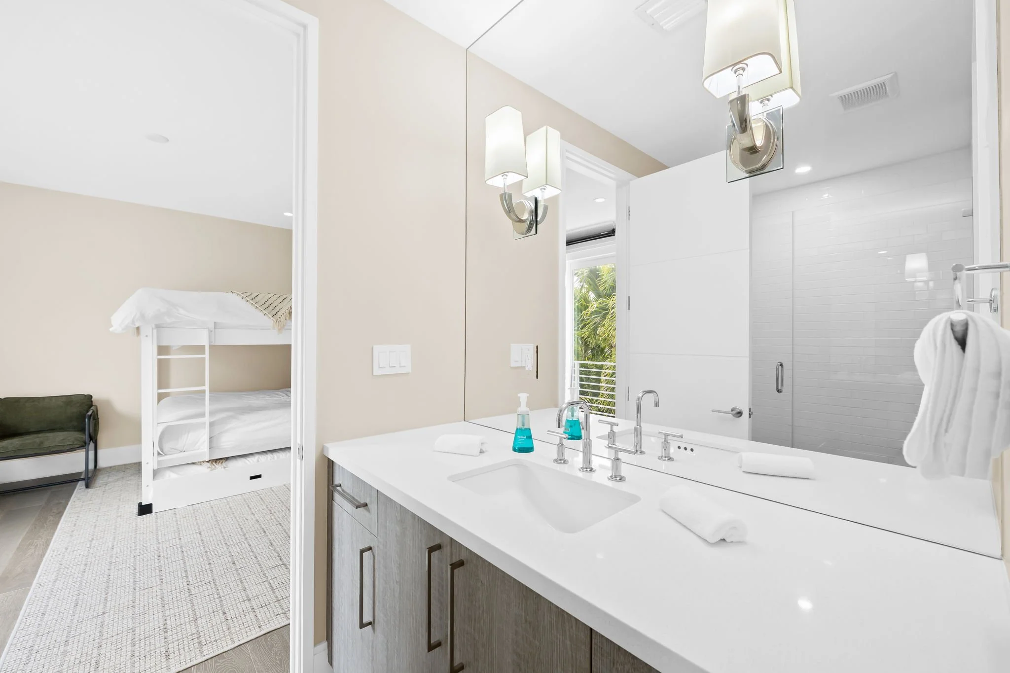 Bright bathroom vanity with wall sconces and garden views — luxury vacation home, Sun Haven Collection.