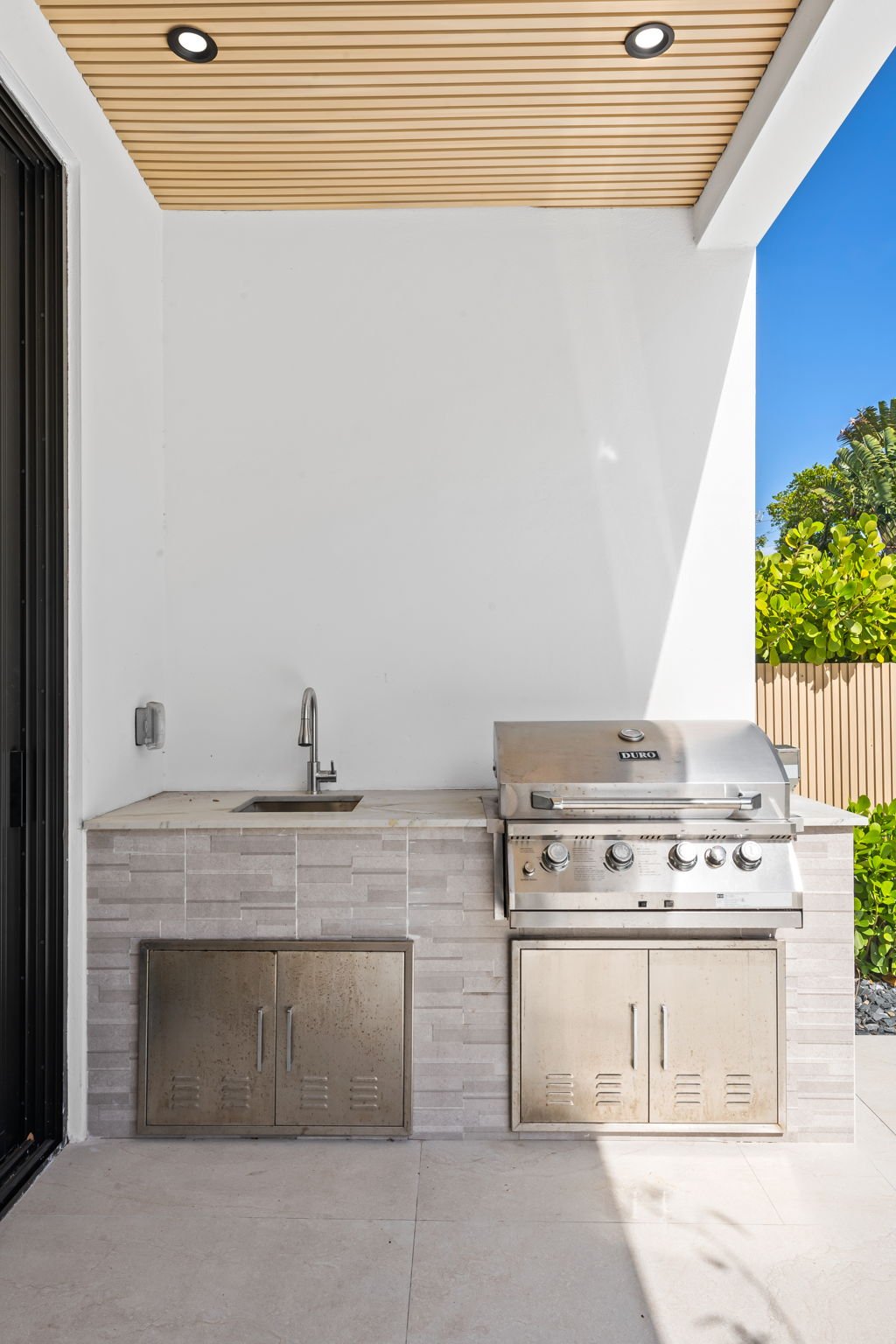 Covered outdoor kitchen with built-in stainless steel grill — Sun Haven Collection luxury vacation rental.