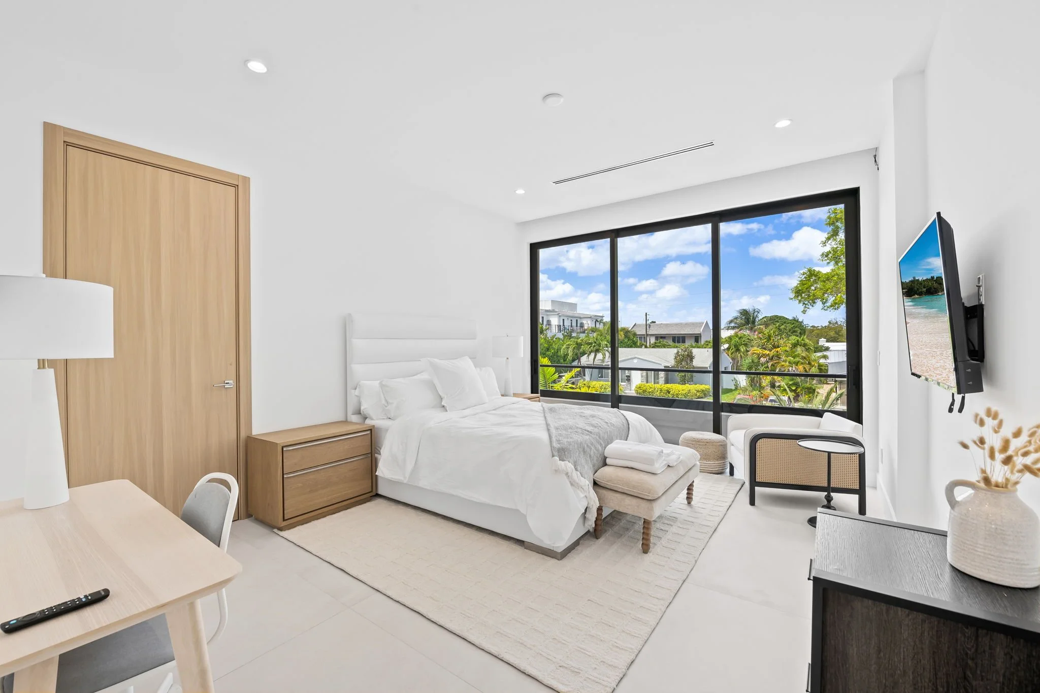 Sun-filled bedroom with smart TV, wooden furniture, and leafy views — luxury vacation rental by Sun Haven Collection.