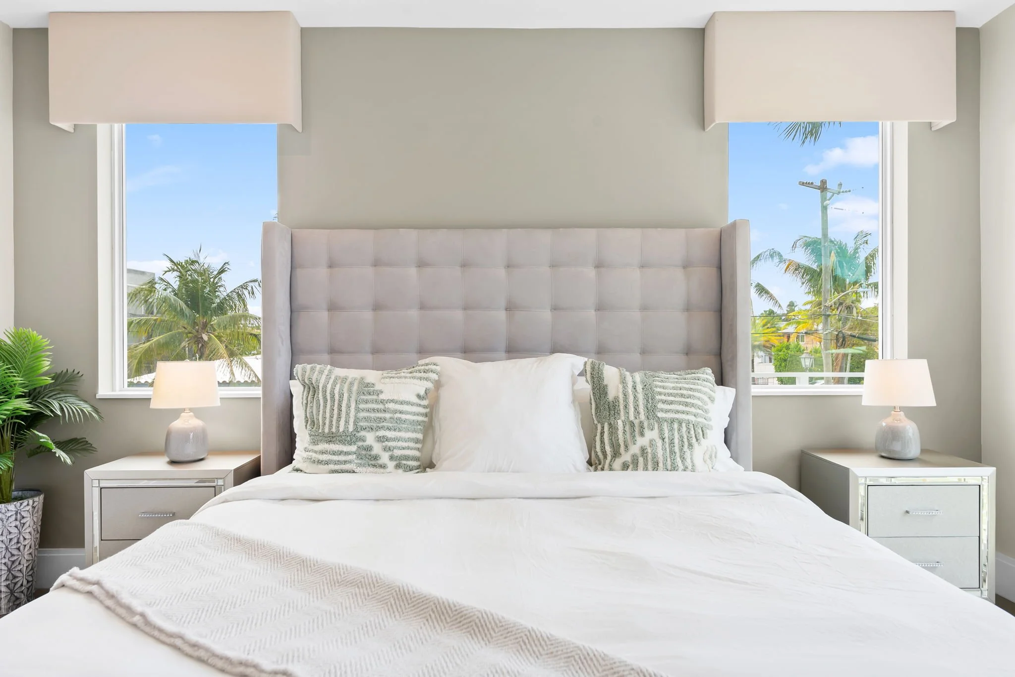 Bright bedroom with palm tree views from two windows — luxury vacation home by Sun Haven Collection.