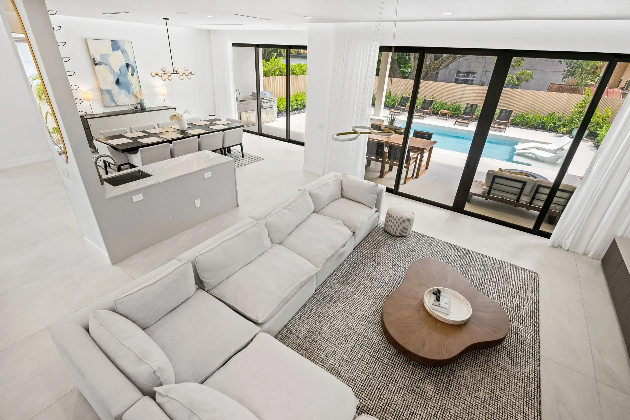 Living room overlooking private pool and outdoor dining area — Sun Haven Collection luxury vacation rental.