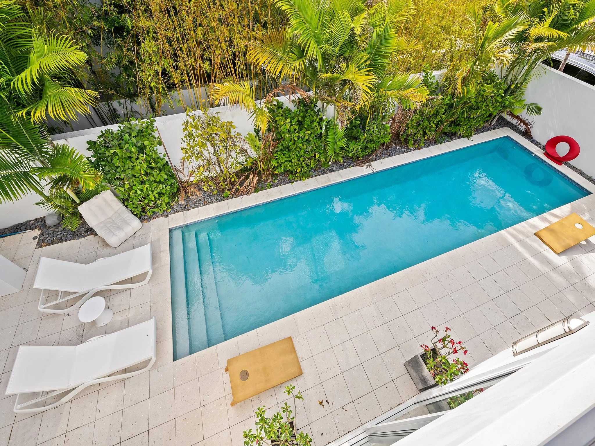 Poolside lounge area with tropical privacy landscaping — luxury vacation home by Sun Haven Collection.