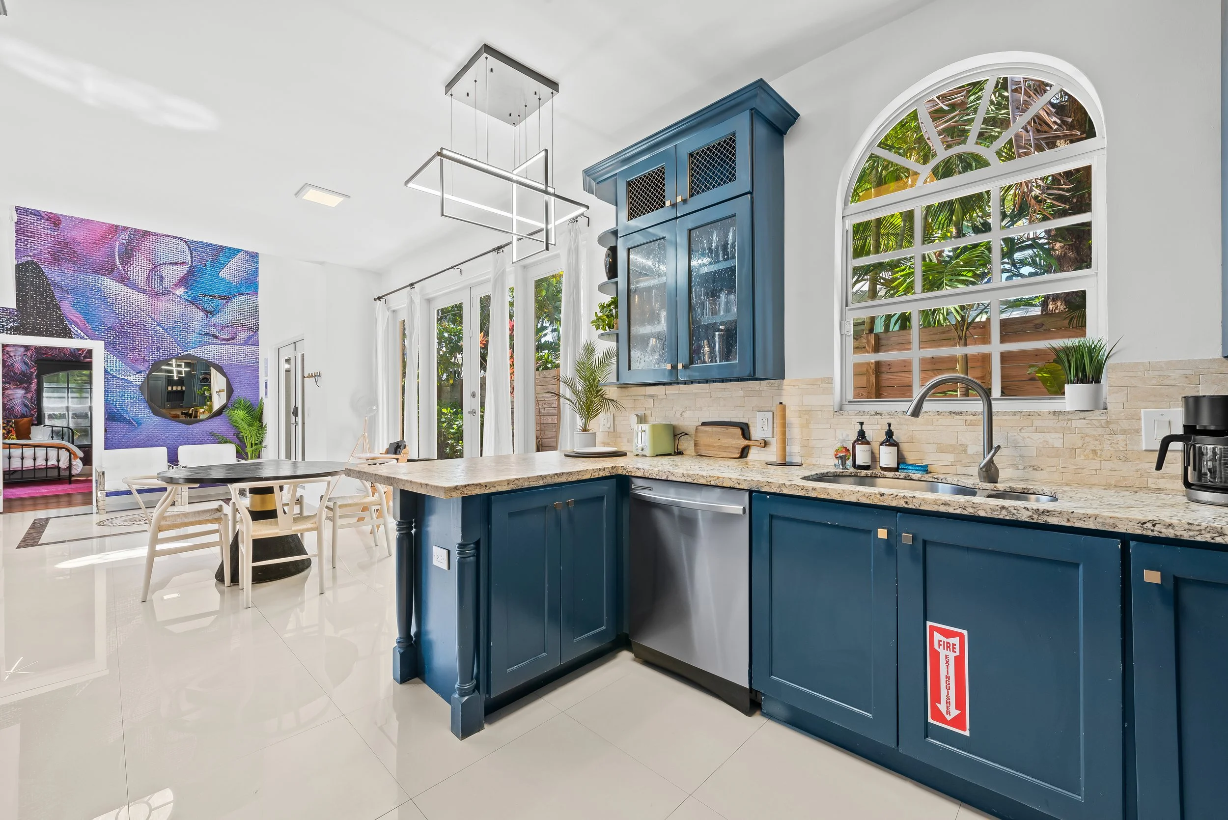 Bright kitchen with designer blue cabinetry and colorful mural — Sun Haven Collection art-inspired vacation rental.