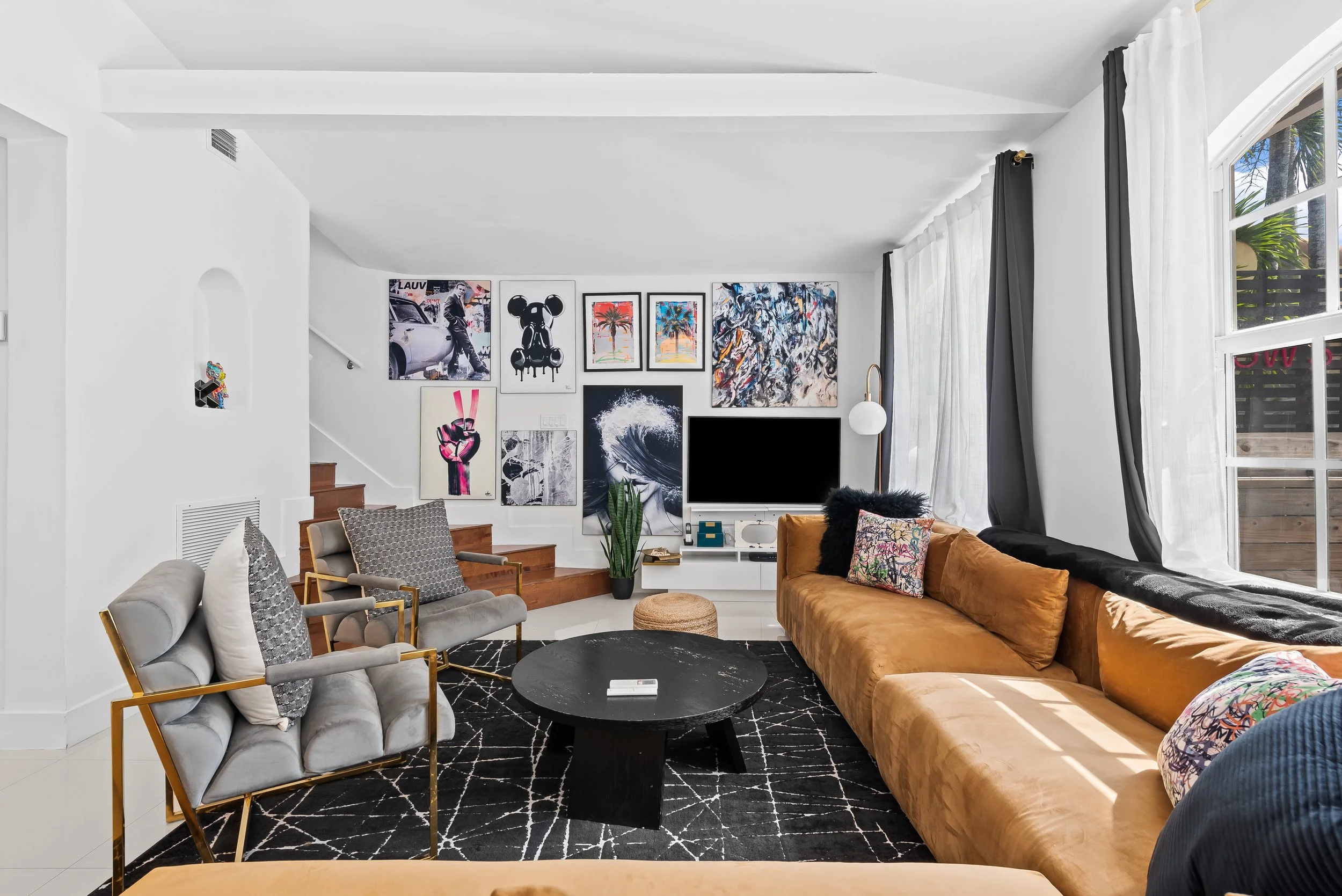 Sunlit living room with curated art collection and designer seating — Sun Haven Collection luxury vacation rental.