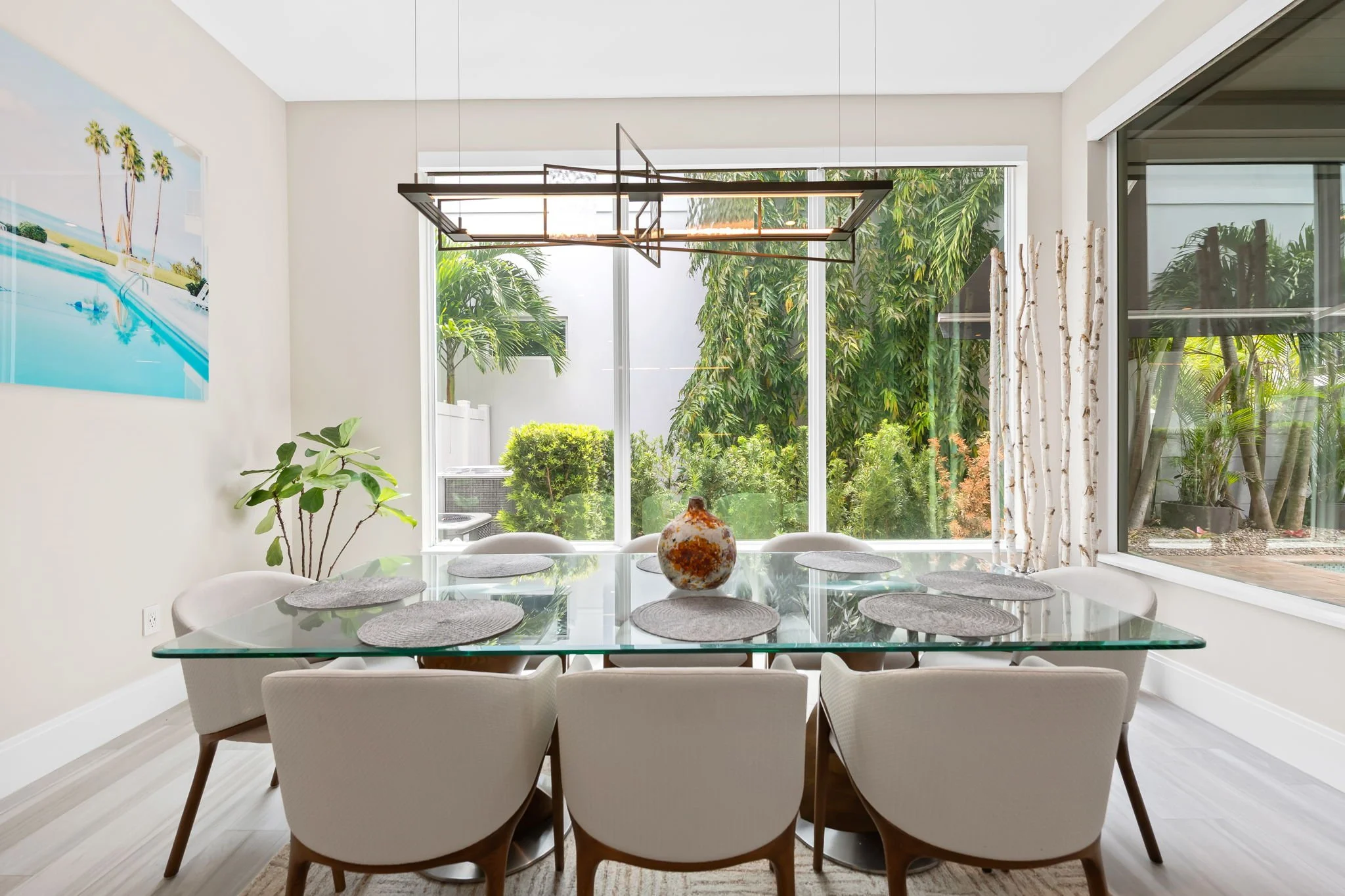 Spacious dining room for seven with tropical wall art — luxury vacation home by Sun Haven Collection.