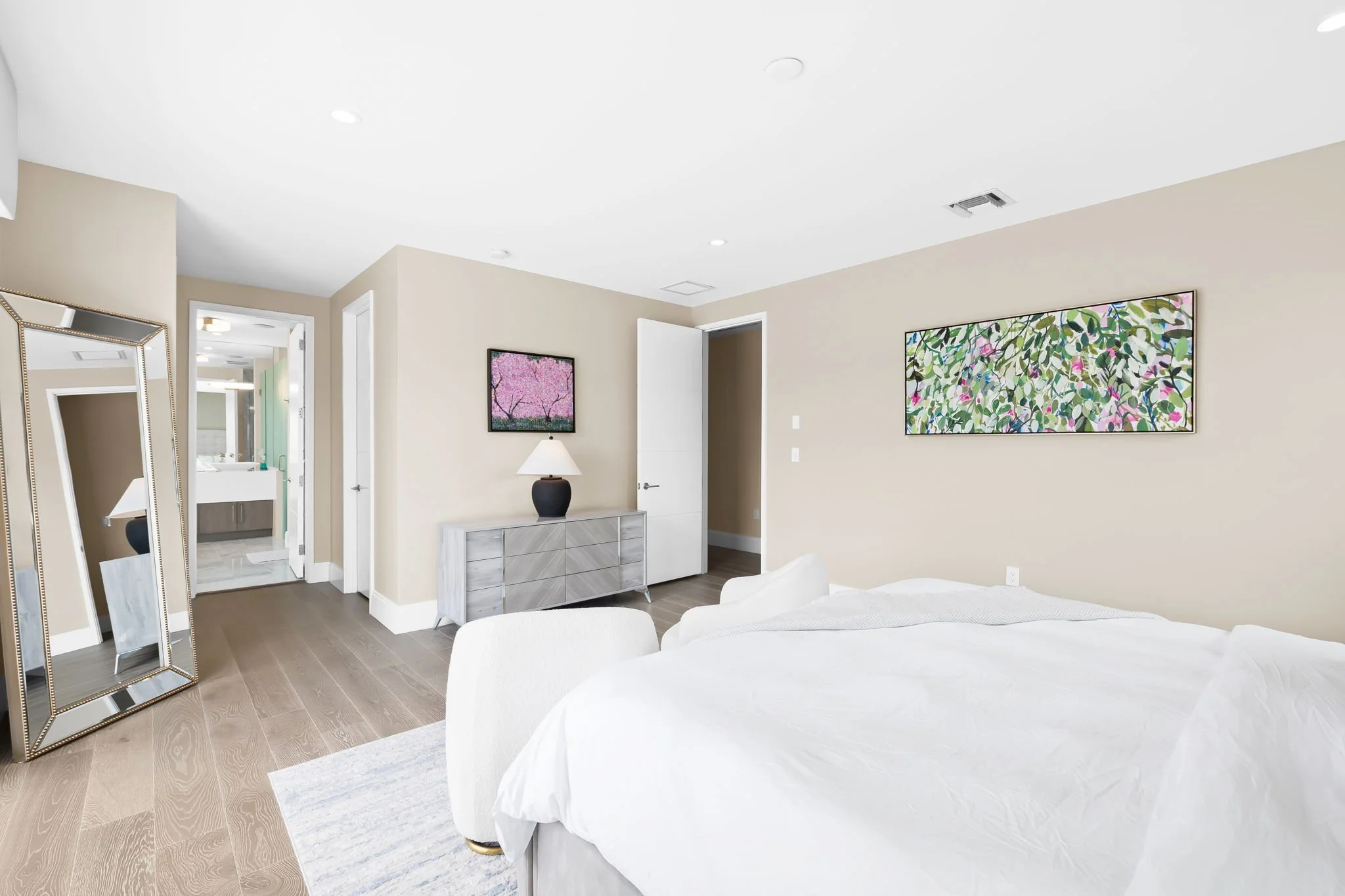 Art-inspired guest bedroom with gold mirror and floral paintings — luxury vacation home, Sun Haven Collection.