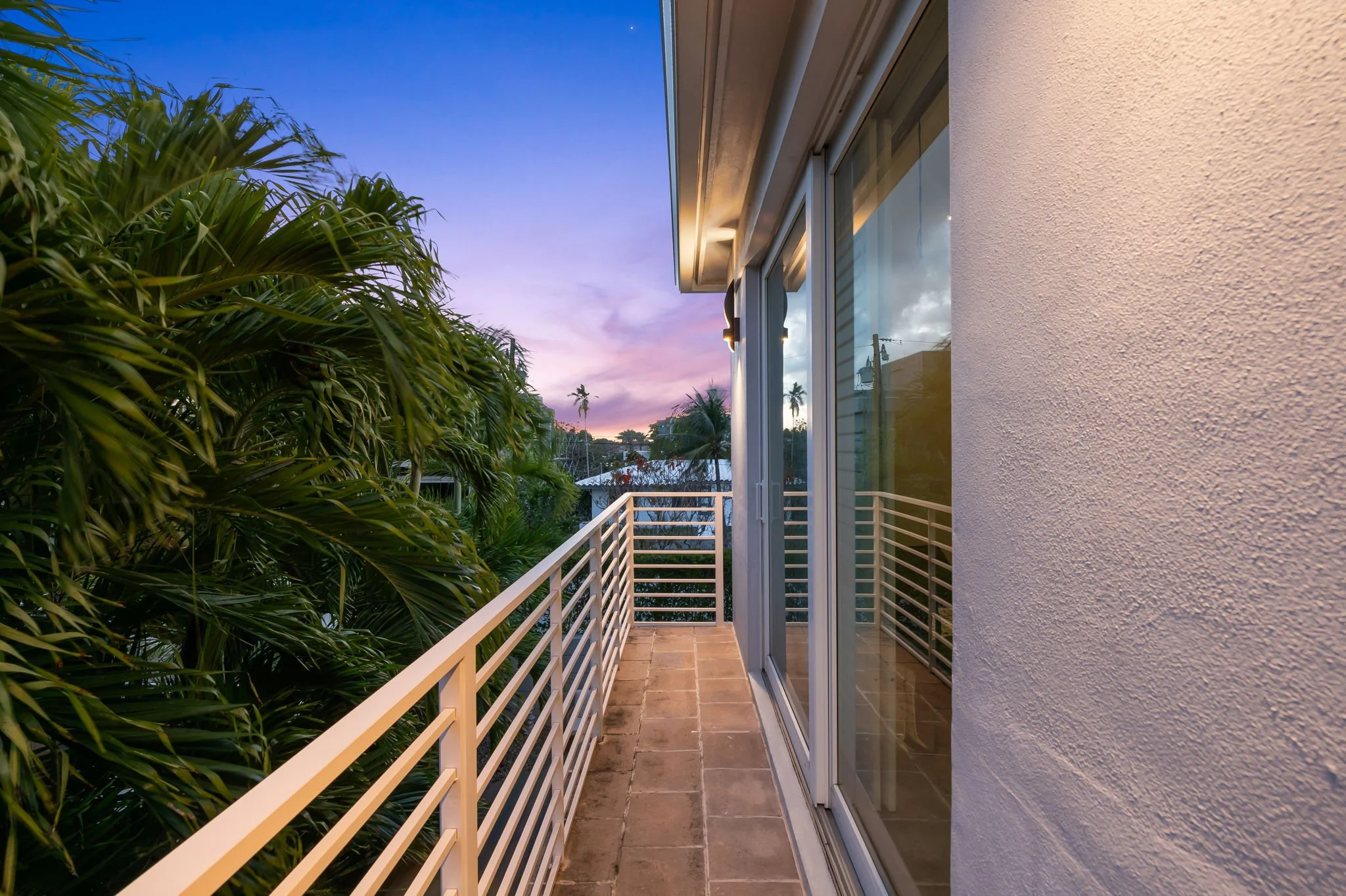 Luxury vacation home illuminated at dusk with tropical landscaping — Sun Haven Collection, Fort Lauderdale.