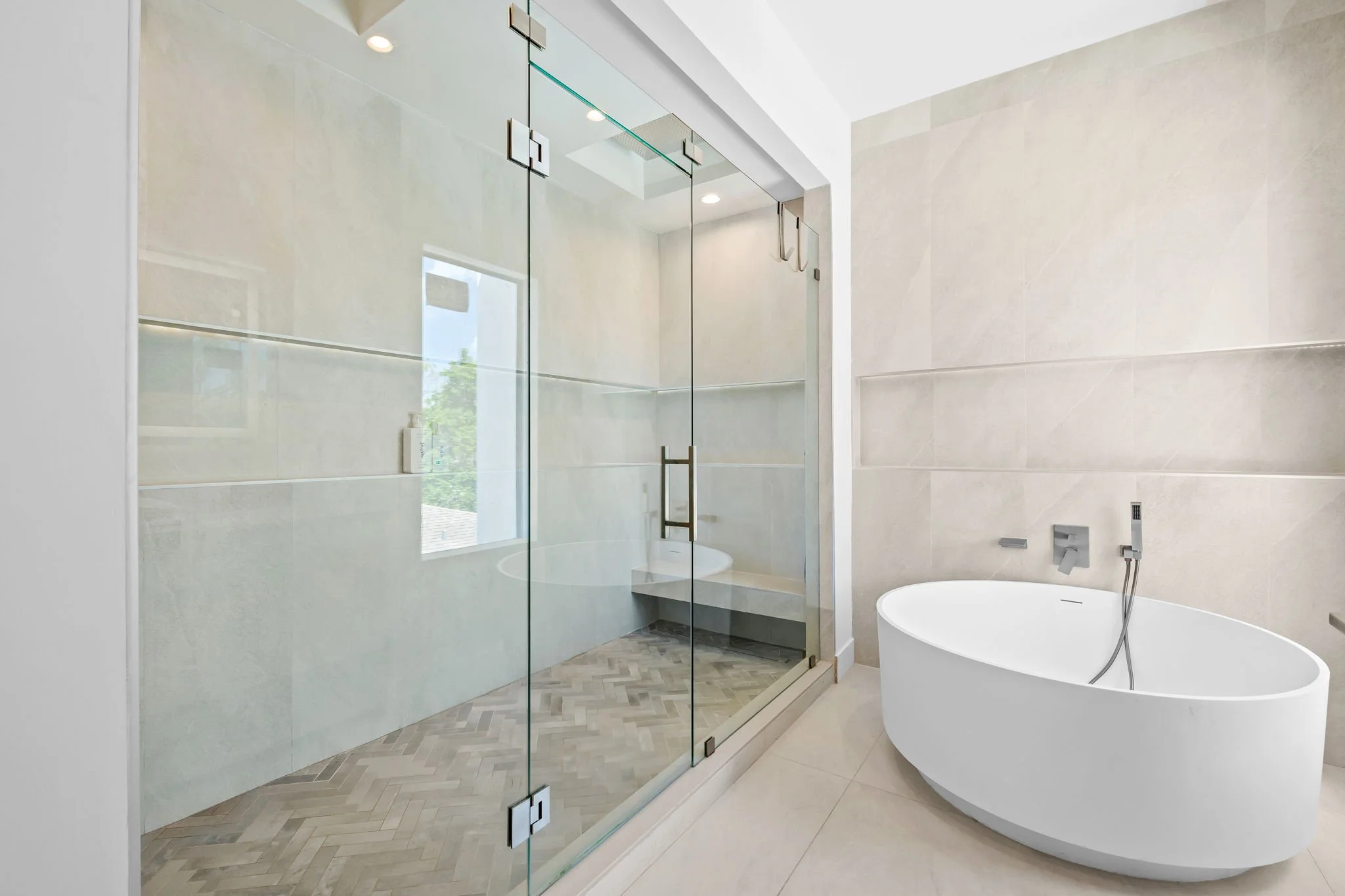 Spa-style bathroom with freestanding soaking tub and glass rain shower — luxury vacation home by Sun Haven Collection.