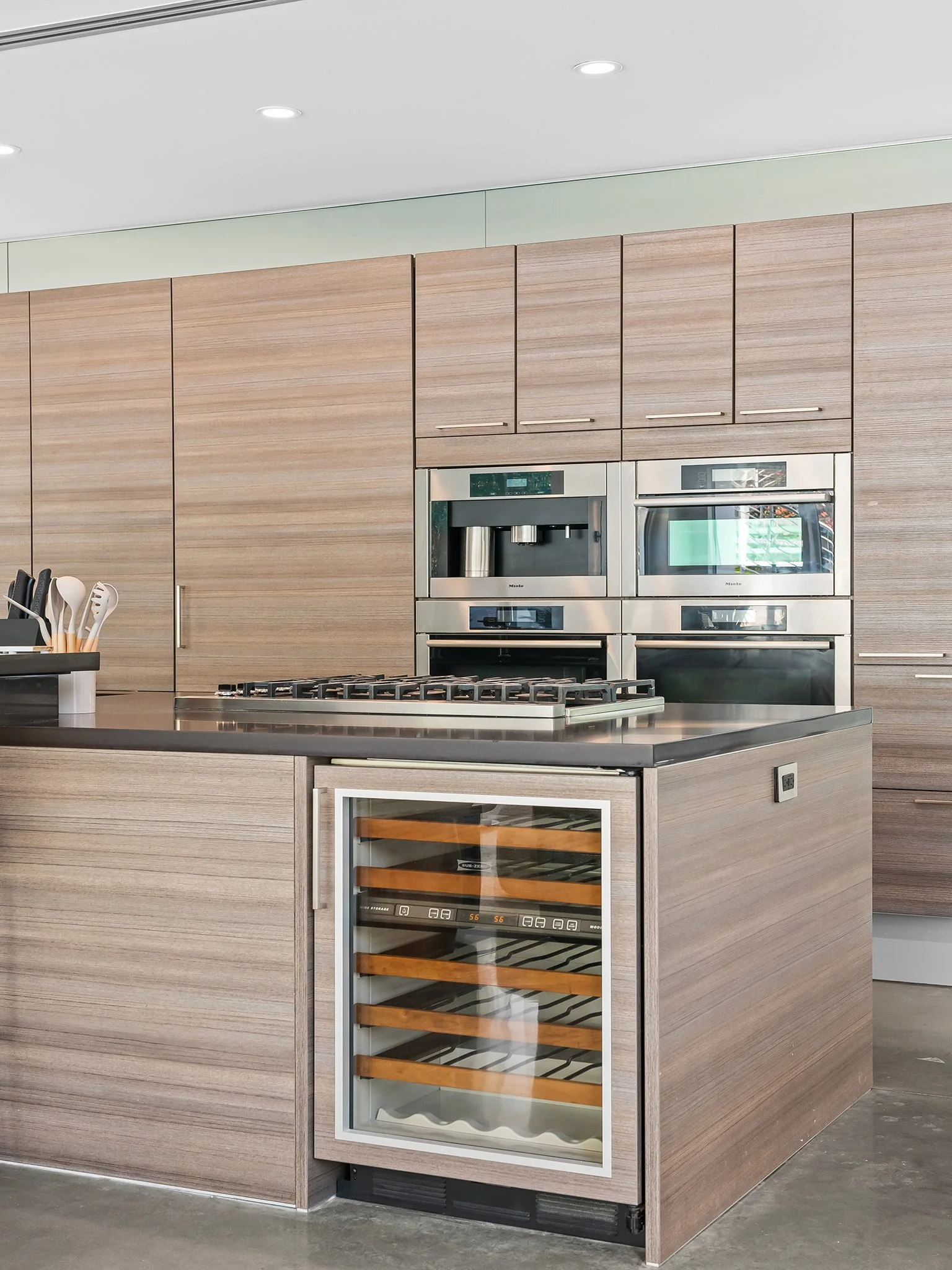 Kitchen with wood cabinets, a built-in coffee machine, a microwave, and a wine cooler.